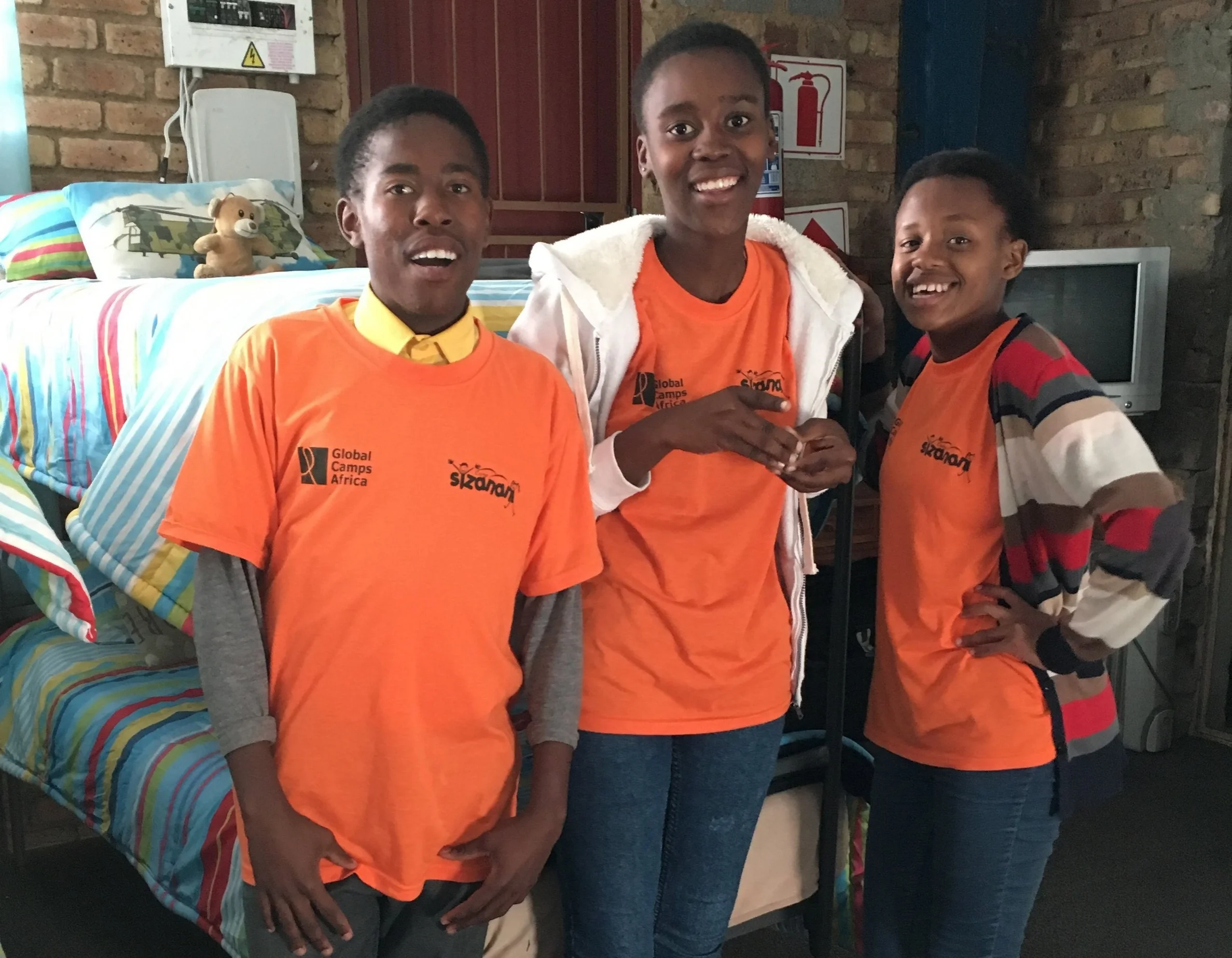Mpho* and his fellow campers standing beside the bed where he slept at Banakekeleni Orphanage as a young child.