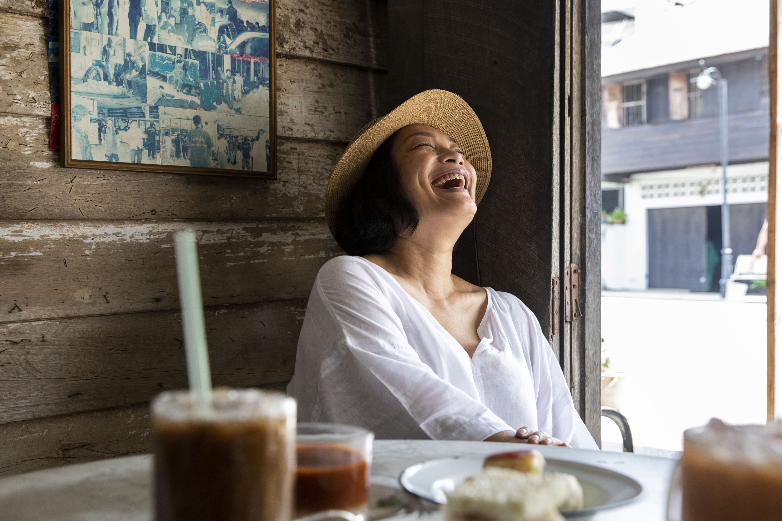  Chutatip “Nok” Suntaranon laughs while having an afternoon coffee in an old shop in Yantakhao, Thailand on Saturday, April 16, 2022. Nok traveled from Philadelphia to her home, Thailand, to visit with family and research for her upcoming projects.  