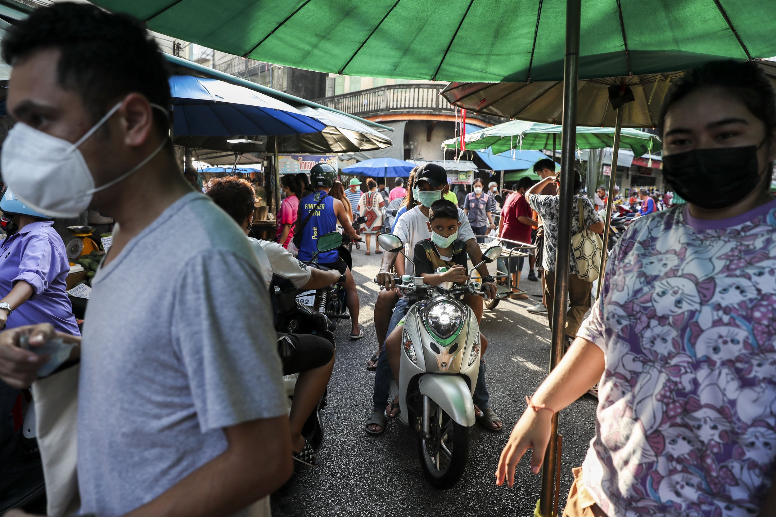  People navigate the crowded market on a motorbike in Trang, Thailand on Saturday, April 16, 2022. Shoppers will often pass through markets on motorbike, stopping at stalls to make their purchases.  