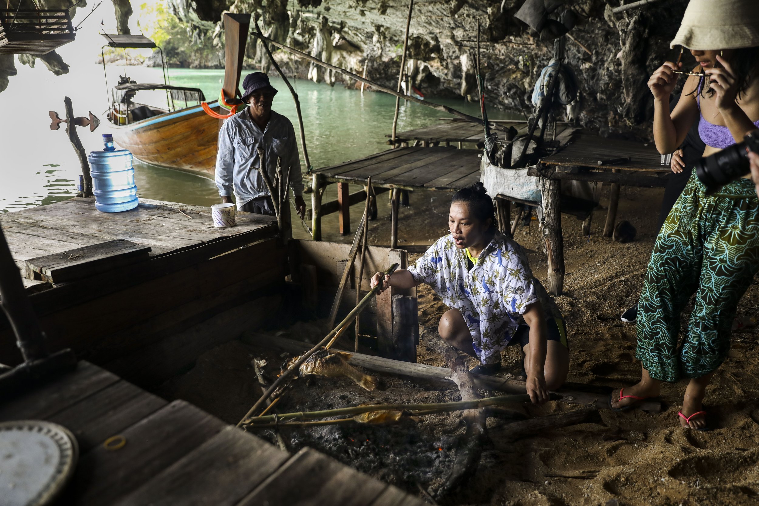  Chutatip “Nok” Suntaranon flips fish cooking over a fire in a fisherman's cave in Koh Yao Noi, Thailand on Tuesday, April 19, 2022. The fisherman's cave in Koh Yao Noi is where fisherman take shelter from storms while out working. 