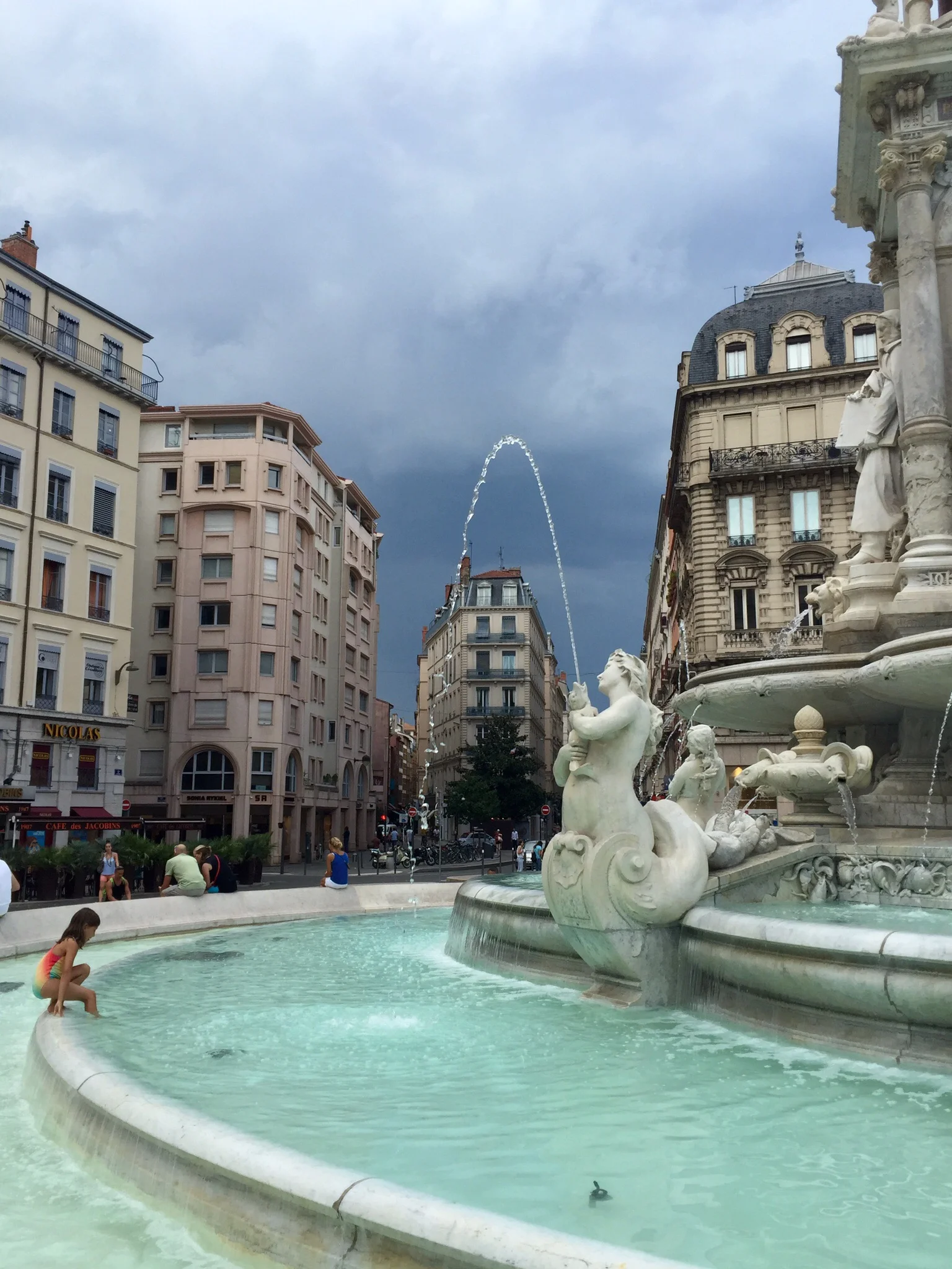 My daughter stepping into the fountain at Place des Jacobins, Lyon, just before the storm arrived