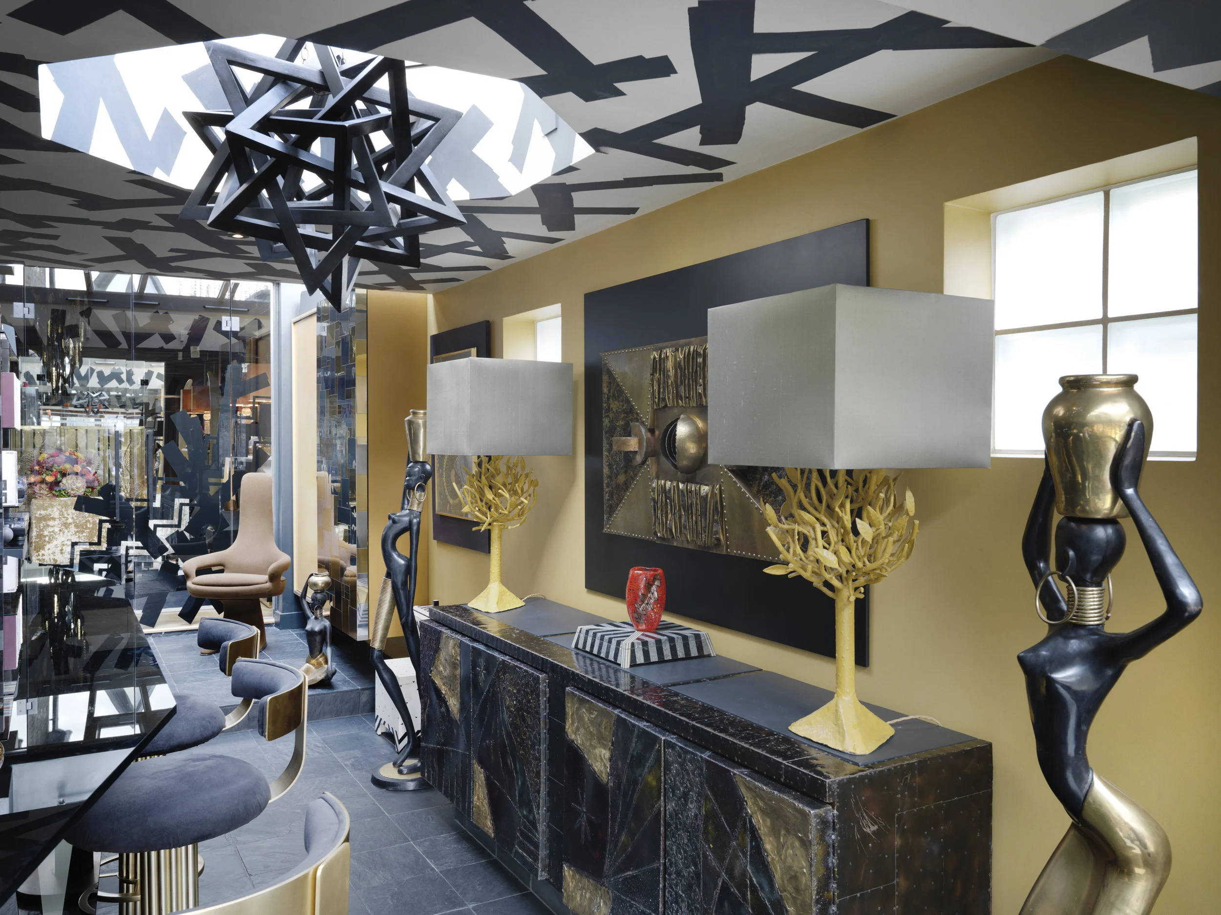 A pair of statuesque ladies very much inspired by Hagenauer designs flank a sideboard by the American Brutalist sculptor and furniture maker, Paul Evans.