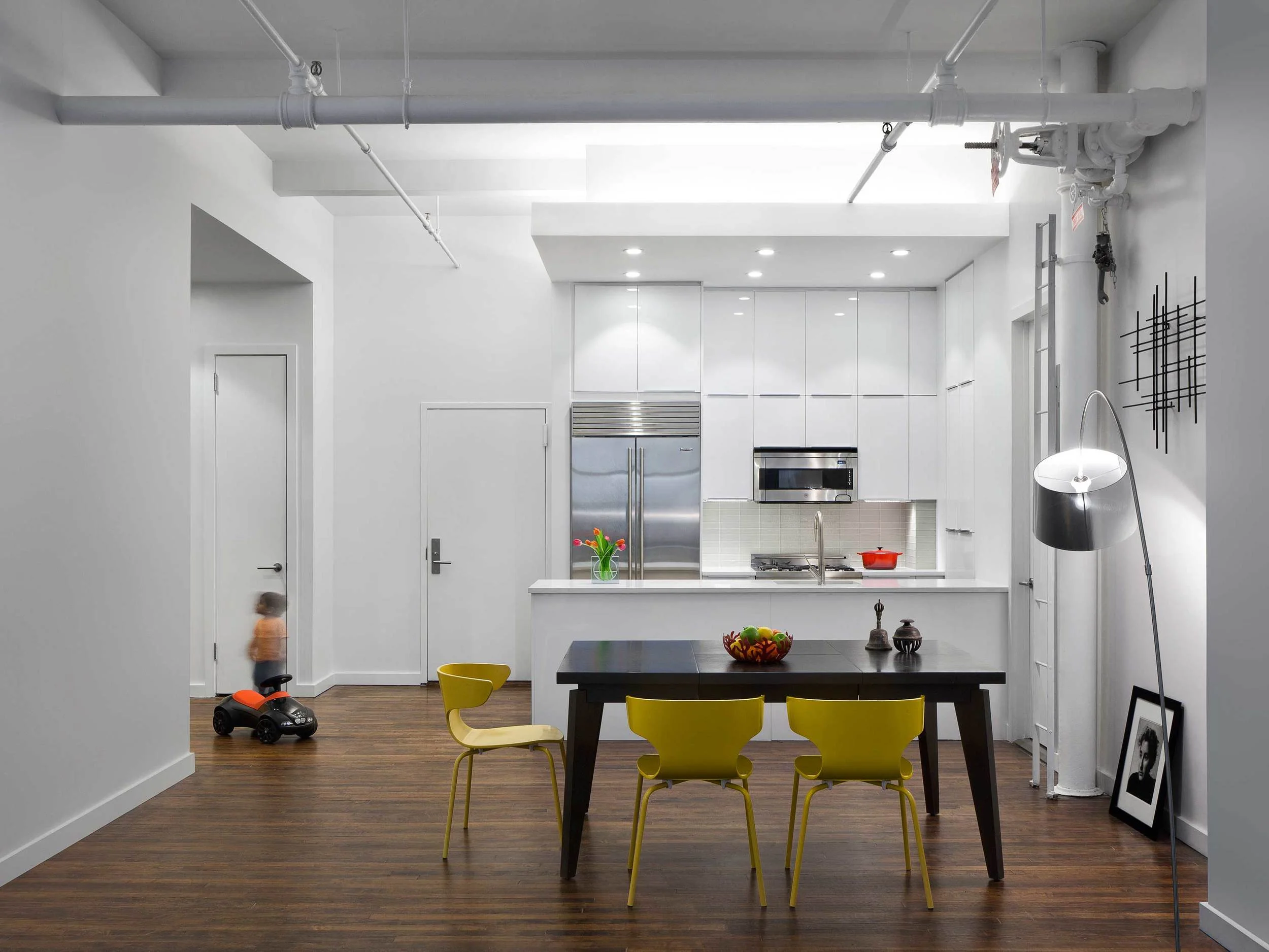 UNION SQUARE LOFT - 2013 This project was a gut renovation of a 1200 SF loft creating a 2-bedroom, 2-bath apartment. The existing apartment had a storage loft, which created a dark low entry, an enclosed kitchen and dated built-ins that robed it of its open loft potential. In our renovation a second bedroom was added, the kitchen was opened up to the living/dining room and a study/family room was created in a formally dark corner. The kitchen features high-gloss cabinetry, glass backsplash, quartzite counter ans stainless appliances. The adjacent study has built in desk stained to match the floor. Photography by Alexander Severin