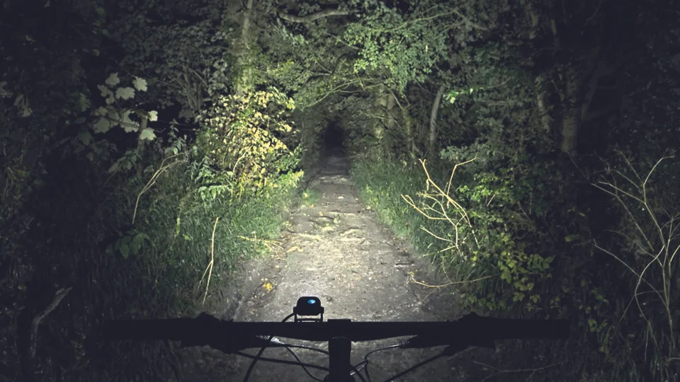 Light output is measured in lumens. This is usually a theoretical best though, and often doesn’t account for lens design or beam spread, which are highly important in how much useful light is kicked onto the trail