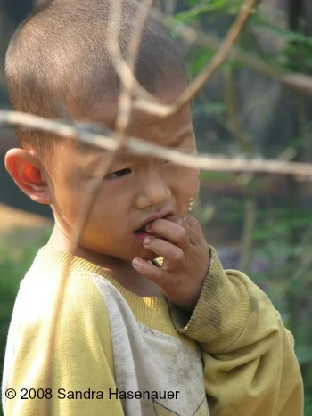 Boy behind wire fence at refugee camp in Thailand
