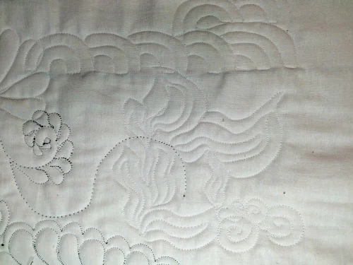 More practice on the back of a previously-used quilt sandwich--green thread showing is from the other side of old practice. All designs in white are new from Leah's class.