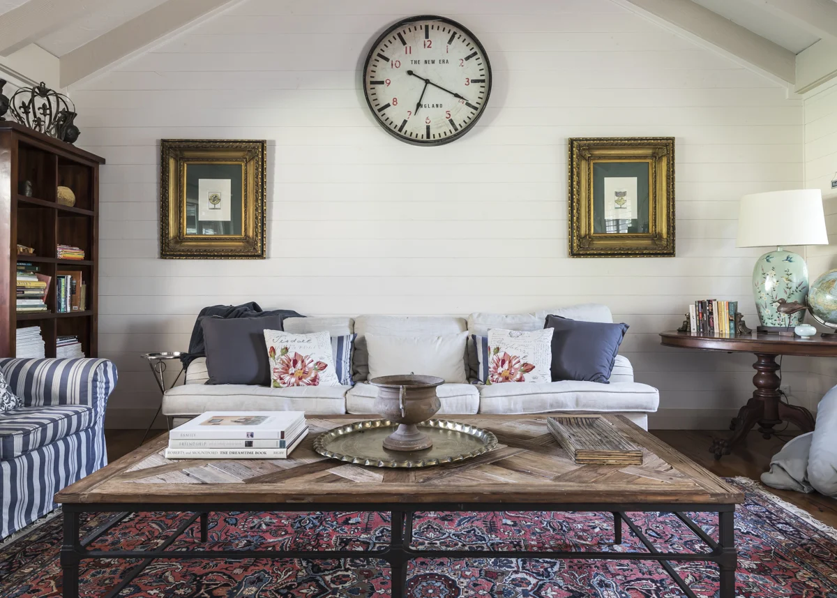 Lounge with a large wall clock, gilt-framed prints and a Persian rug