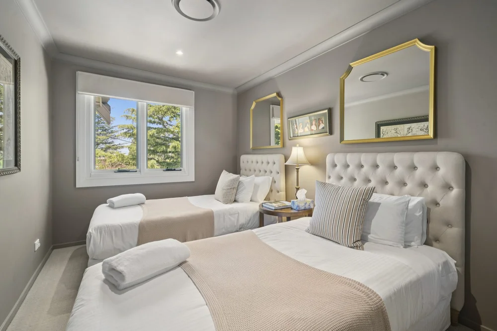 Bedroom 5 with two single beds, upholstered bedheads and gilt mirrors