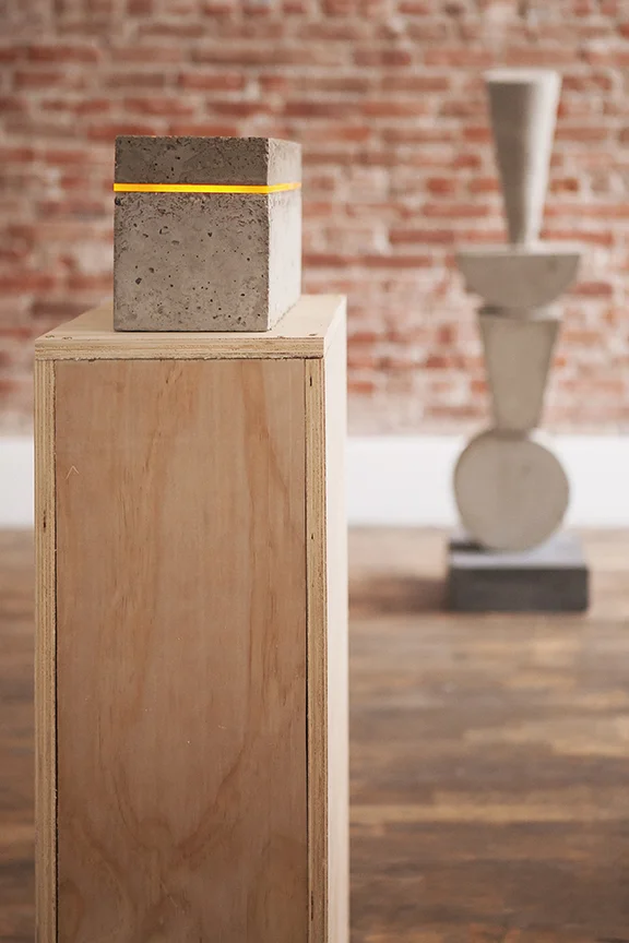 Vibe Transmitter Yellow (foreground) 14" x 9" Concrete, acrylic, LED light Available Vishvamurti (Conqueror of False Leaders) (background) 13" x 13" x 49" Concrete Available