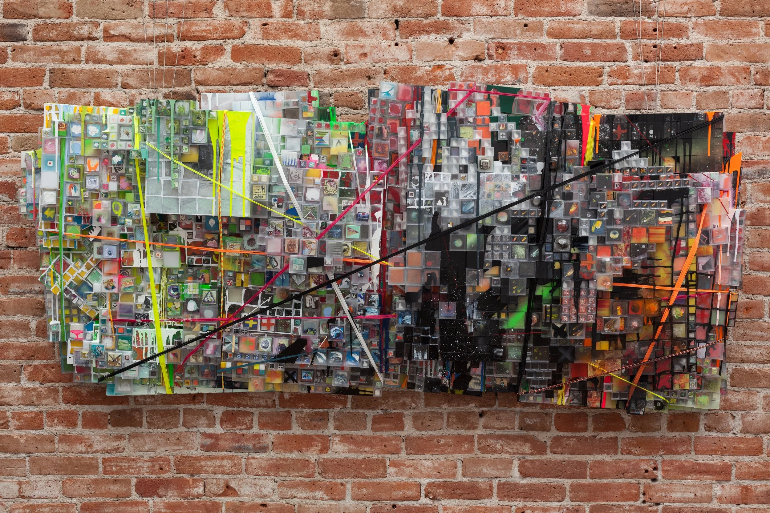 "Though many of Saiz’s works are compelling, the showstopper is the monumental “It’s only working ’til it isn’t,” made up of thousands of little plastic boxes, each containing a minuscule painting. Trussed up with brightly colored cords and painted over in places, the piece takes on a jagged horizontal form that stands out from the wall."
