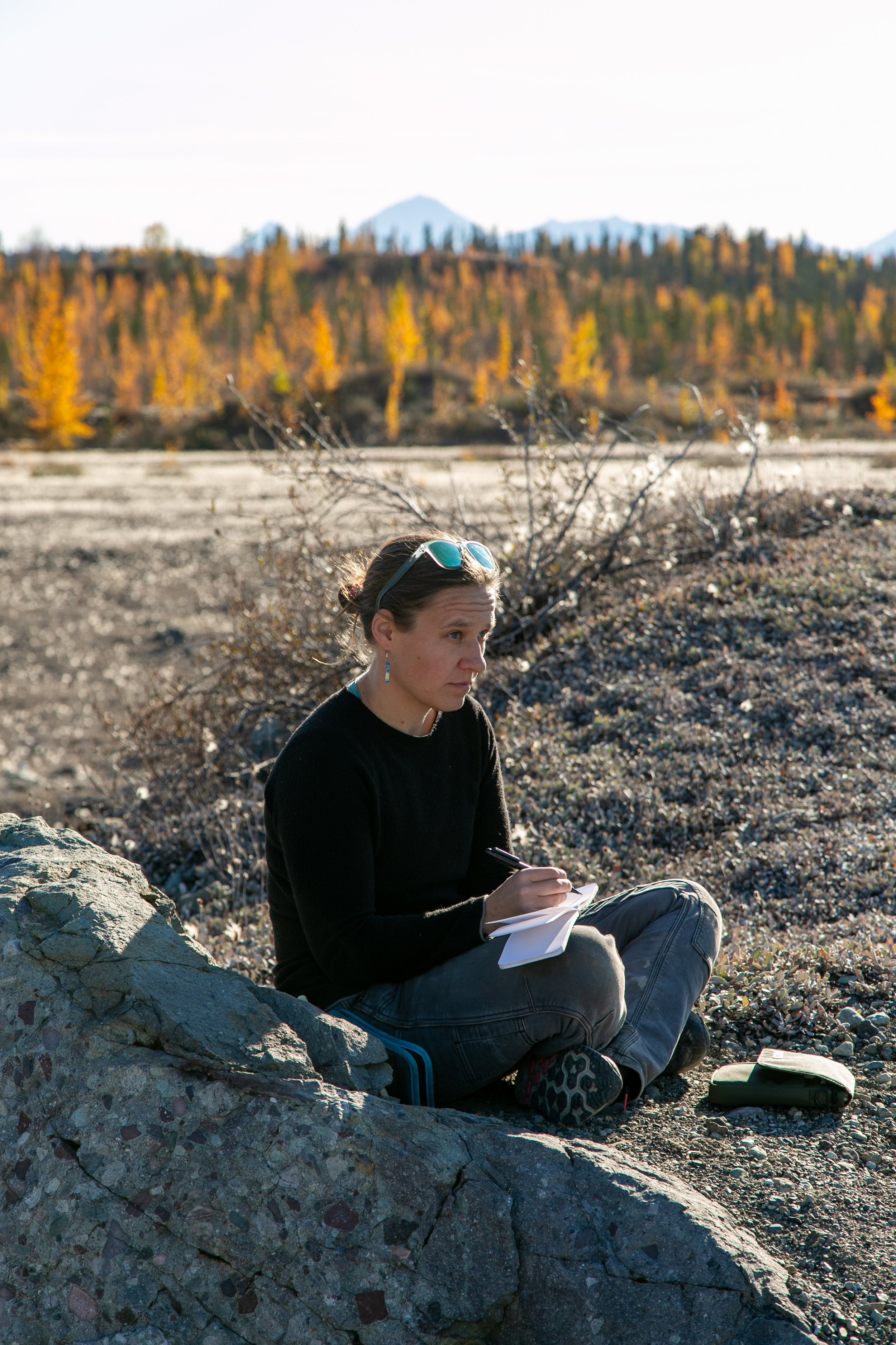Kristin Link sitting outside working in a sketchbook on a sunny autumn day