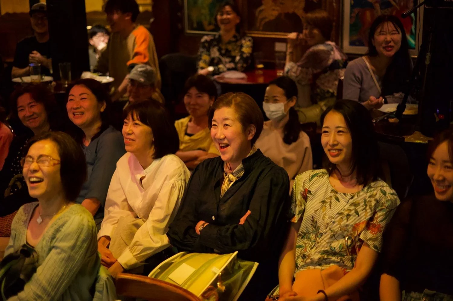 Row of audience members laughing at a live comedy show at What the Dickens! in Ebisu Tokyo | お笑いライブ 初めて 席 恵比寿 即興コメディ | Pirates of Tokyo Bay