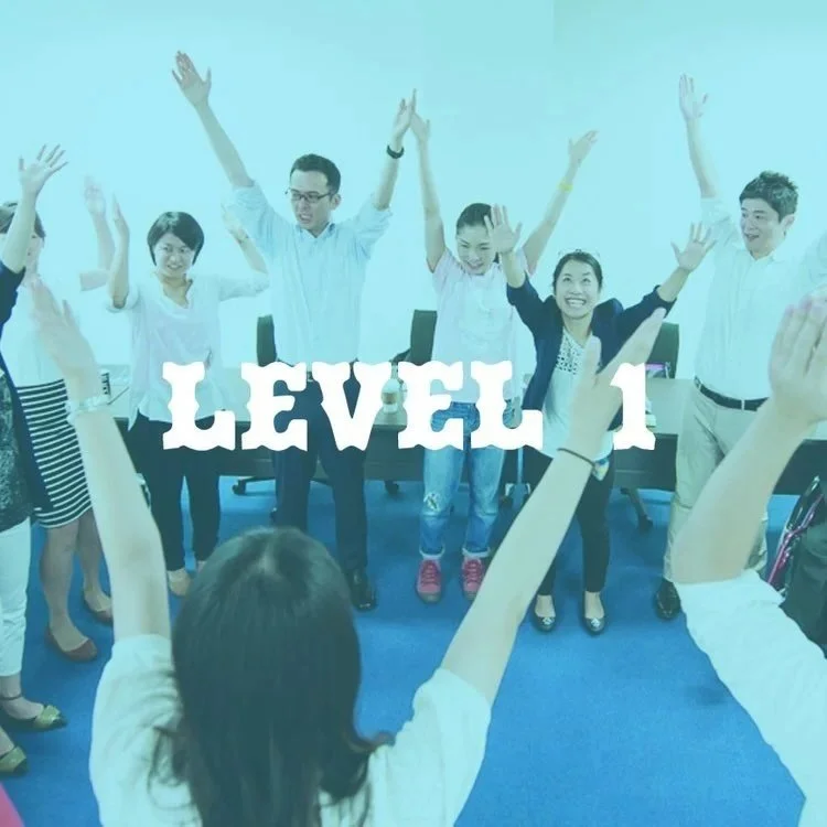 Beginner improv students celebrating with hands raised after Level 1 training 即興コメディ 初級トレーニング 東京 Pirates of Tokyo Bay