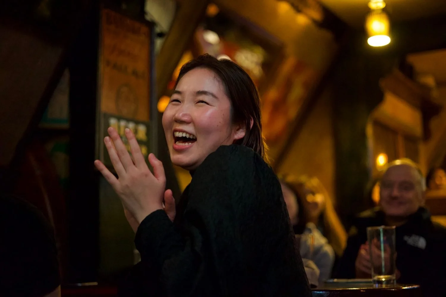 Woman laughing and clapping during an improv comedy show at What the Dickens! pub in Ebisu Tokyo | お笑いライブ 一人 初めて 恵比寿 | Pirates of Tokyo Bay