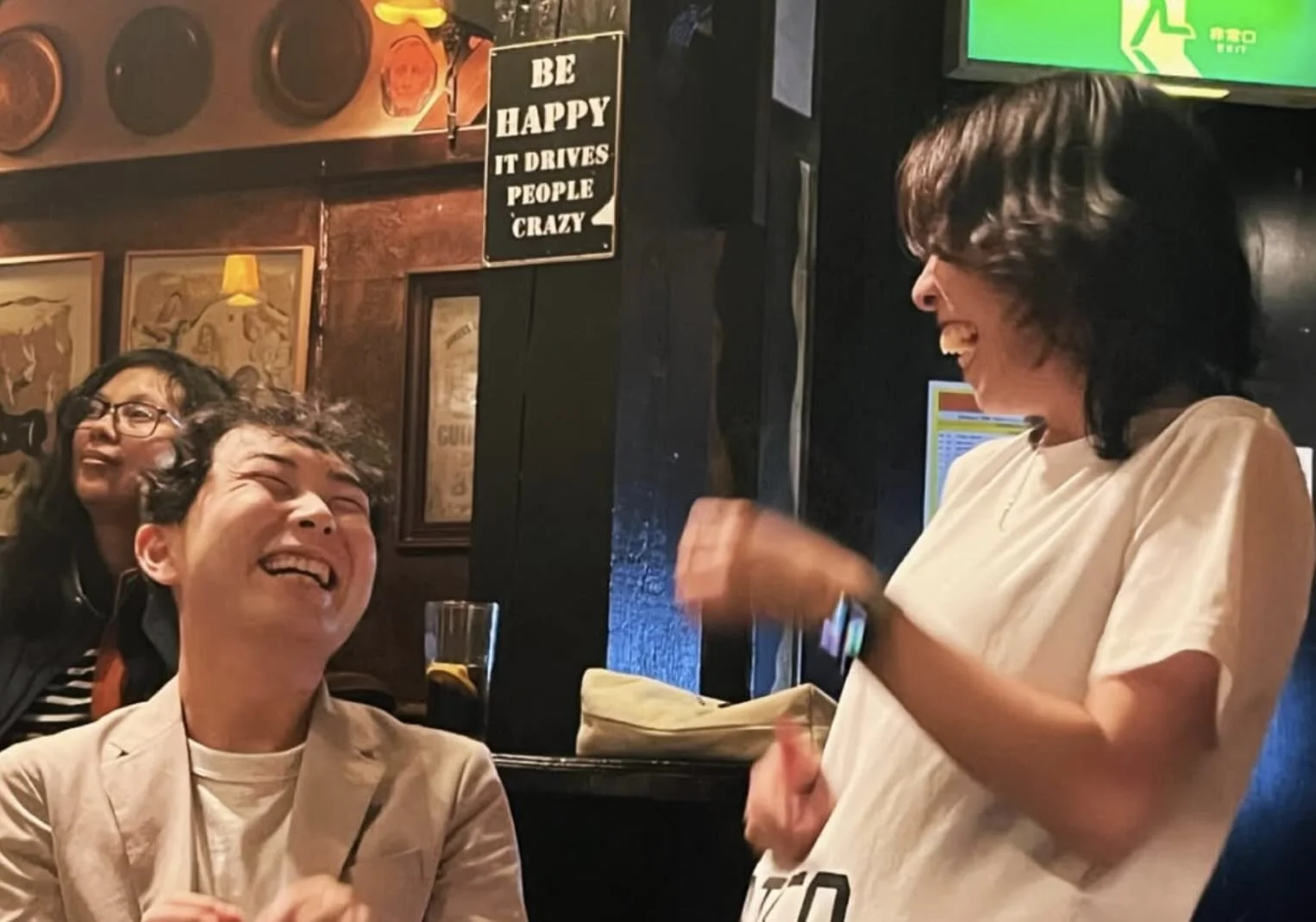 恵比寿のWhat the Dickensで行われたパイレーツ・オブ・東京湾の即興コメディショーで、メンバーが観客と一緒に笑っている様子。 Pirates of Tokyo Bay member laughing with an audience member during a live improv comedy show at What the Dickens in Ebisu.