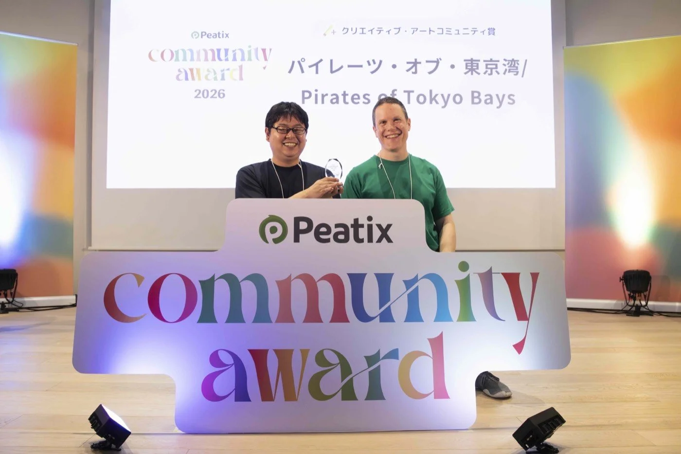 Two members behind the "community award" sign in Tokyo, Japan