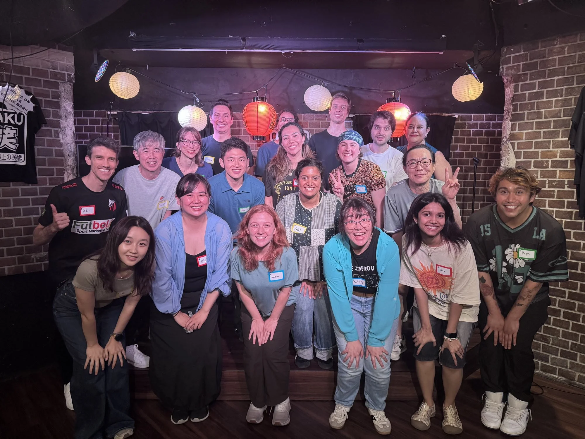渋谷のTokyo Comedy Barのステージで笑顔で並ぶ、パイレーツ・オブ・東京湾の即興コメディ・オーディション参加者たち。