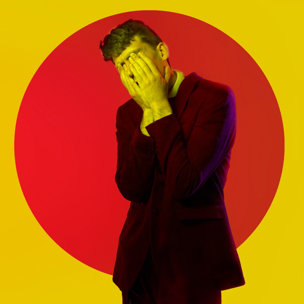A colour gel portrait of Danny, lead singer from Shrug Life. The photo shows Danny holding his face, no facial features are visible in this portrait. The photo was taking in Deadly Studios in Finglas.
