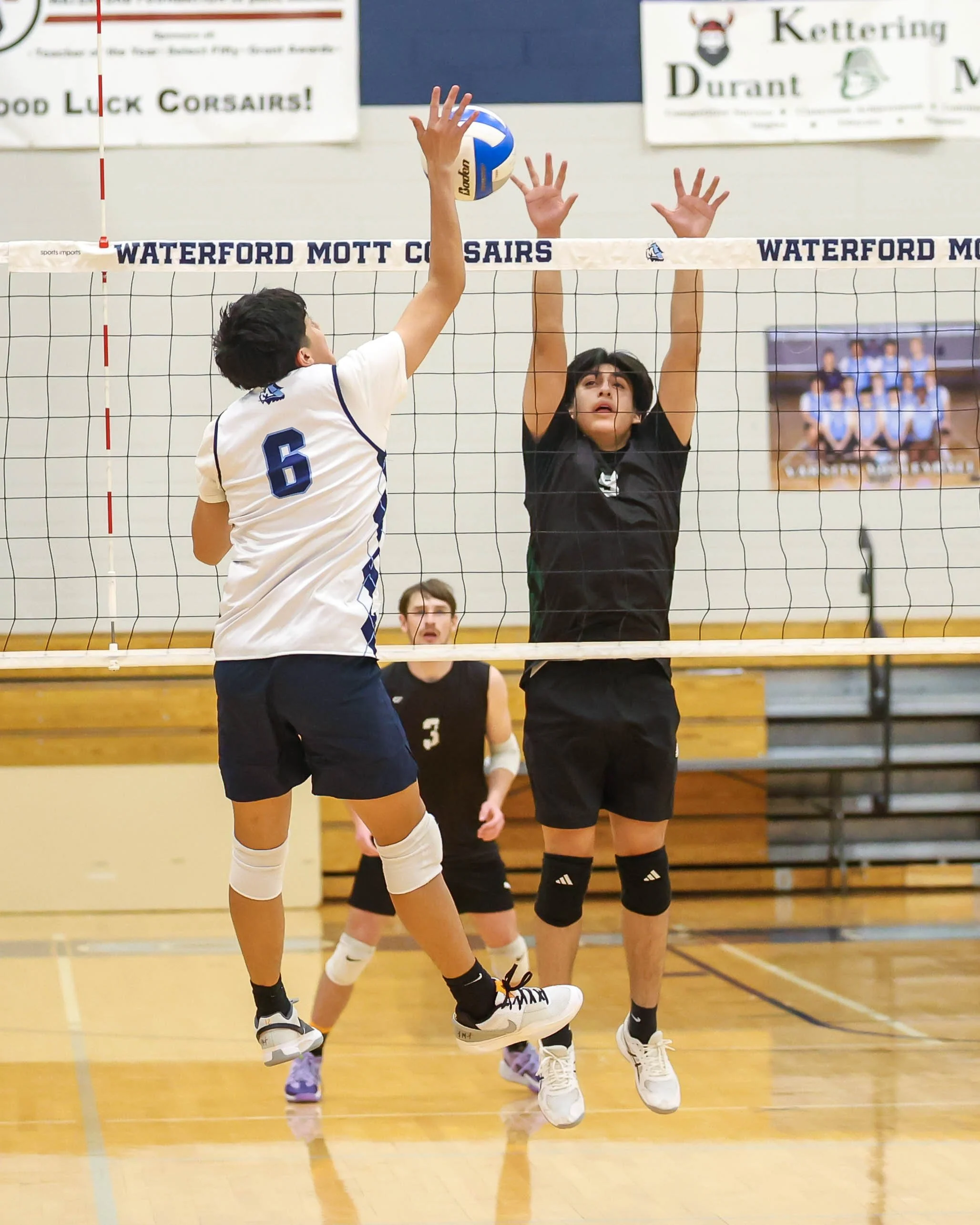 Mott #6 spikes the ball and Kettering #9 tris to block it