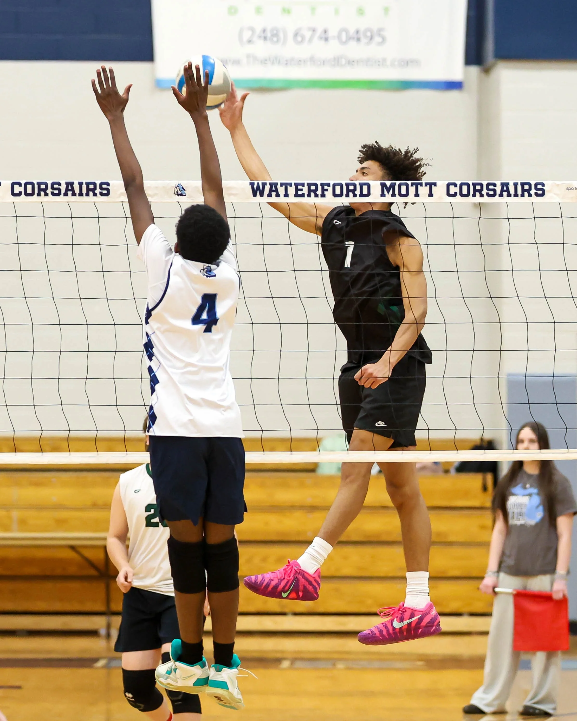 Kettering #1 hits the ball with Mott #4 trying to block it