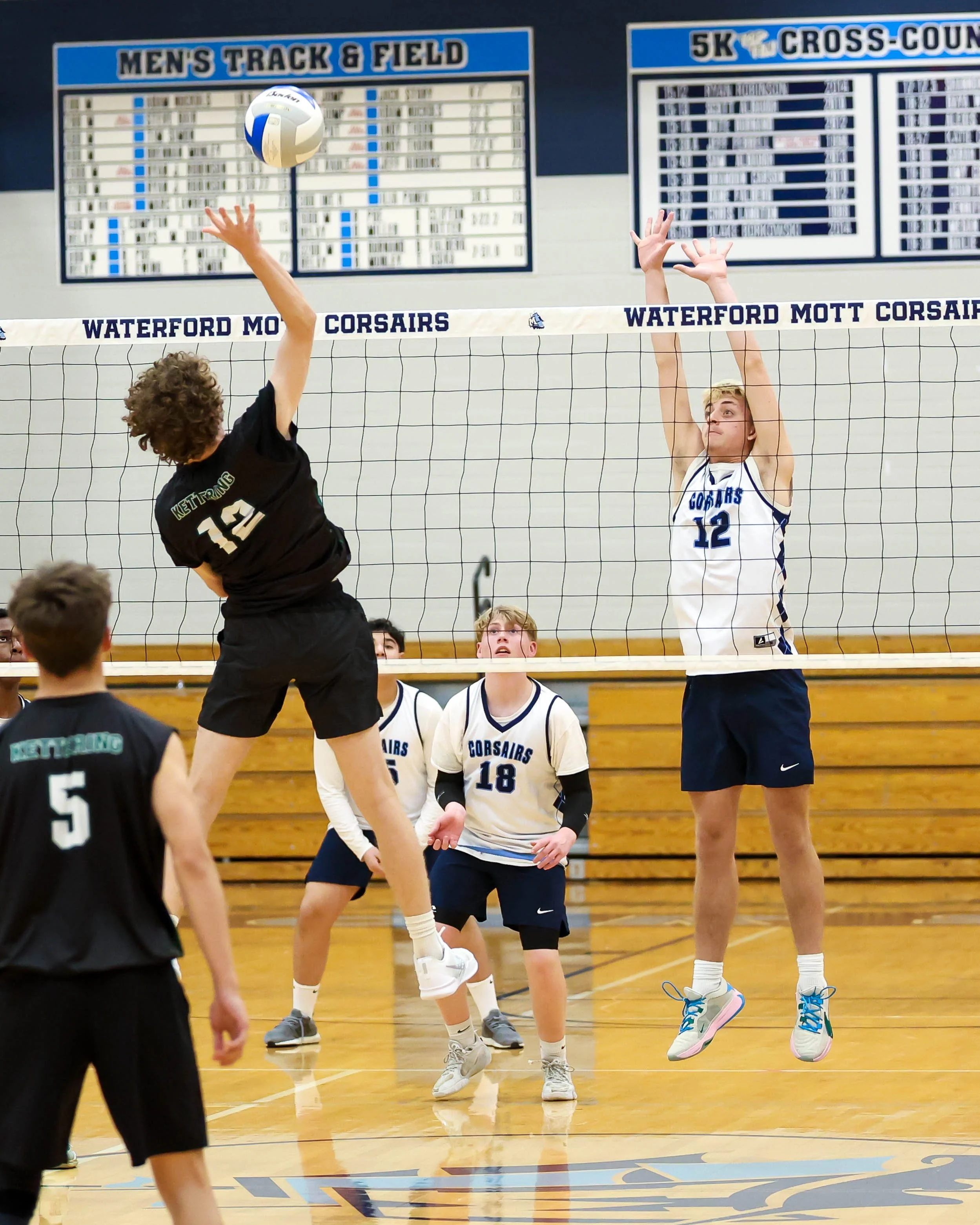 Kettering #12 spikes the ball and Mott #12 tries to block it