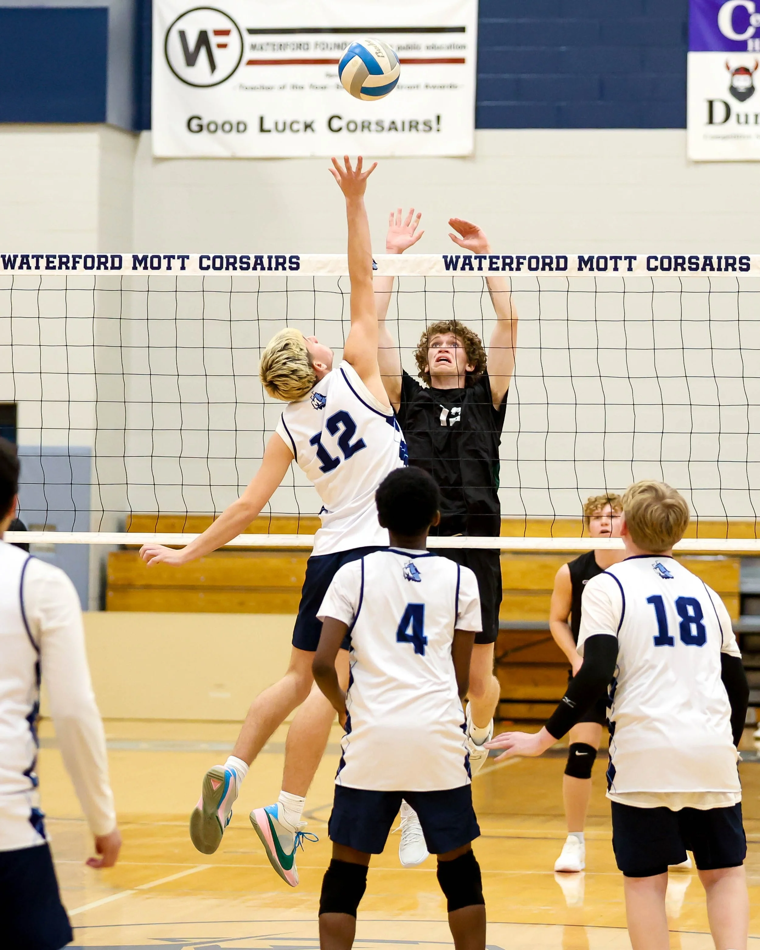 Mott #12 spikes the ball with Kettering #12 trying to block it