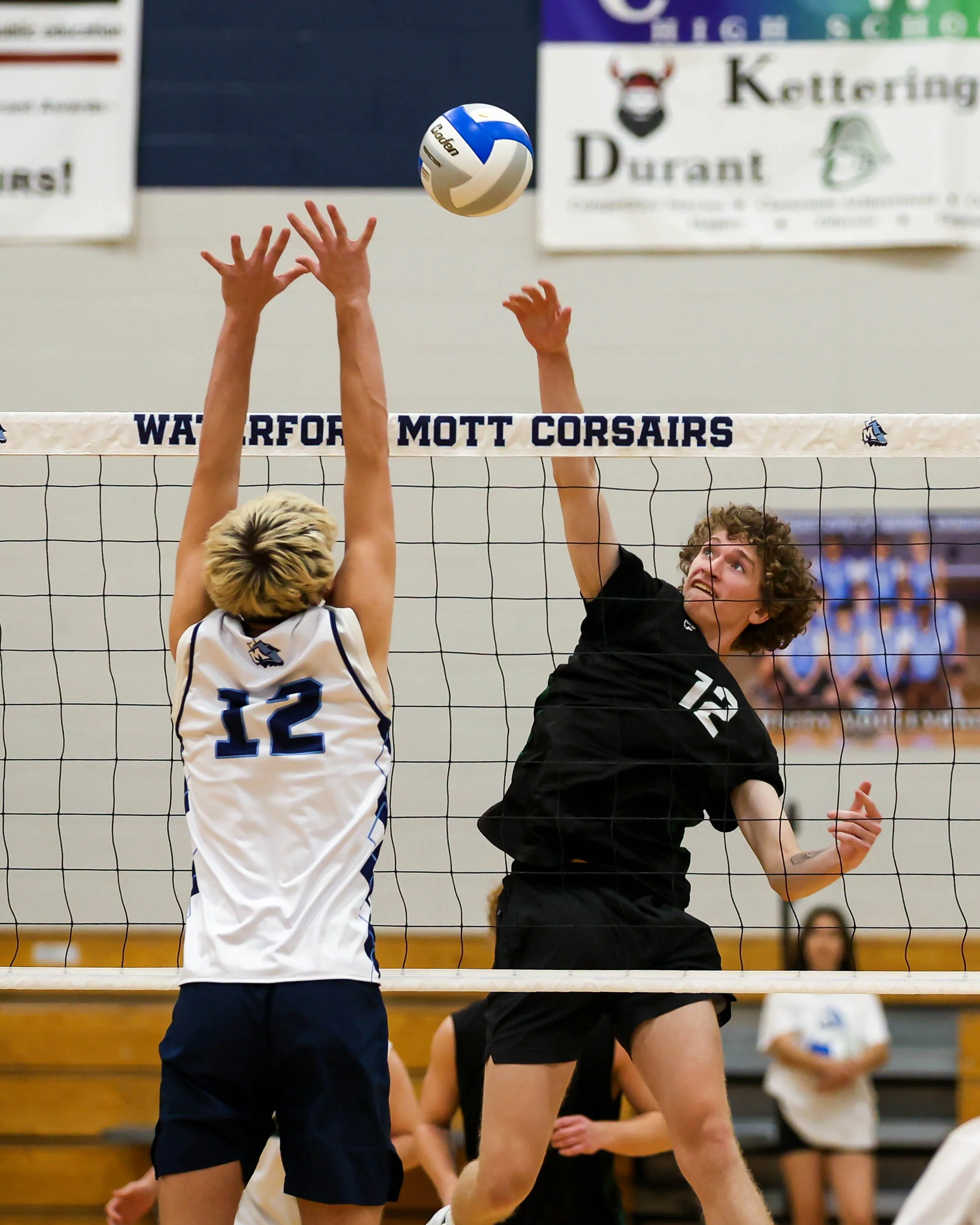 Kettering #12 spikes the ball and Mott #12 tres to block it