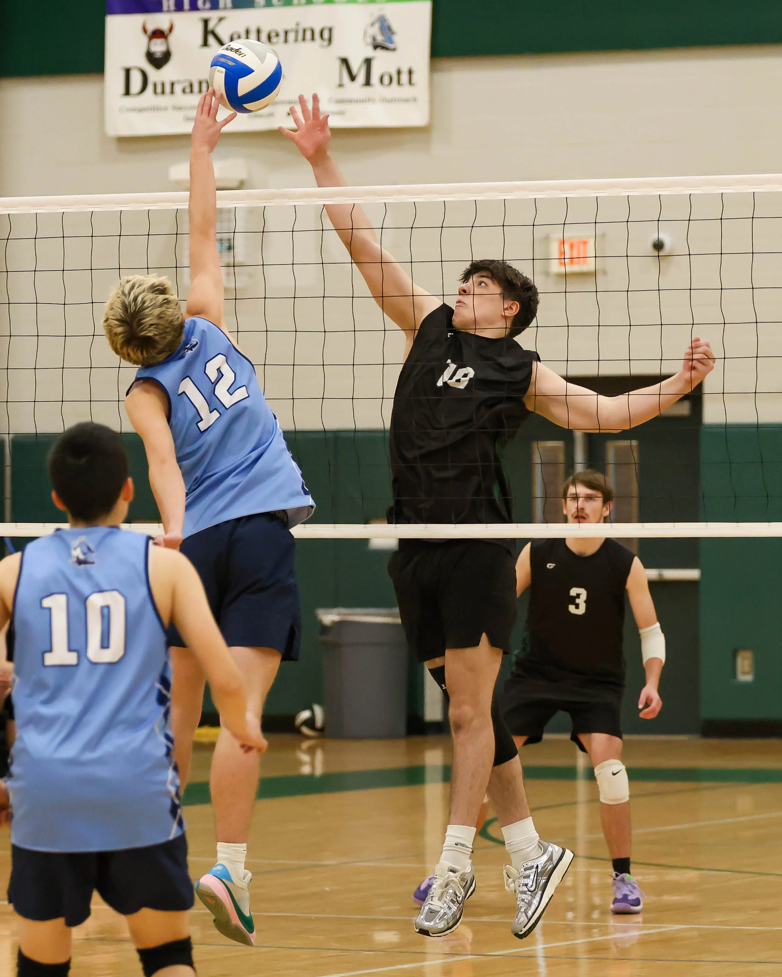Mott #12 spikes the ball Kettering #10 goes for the block