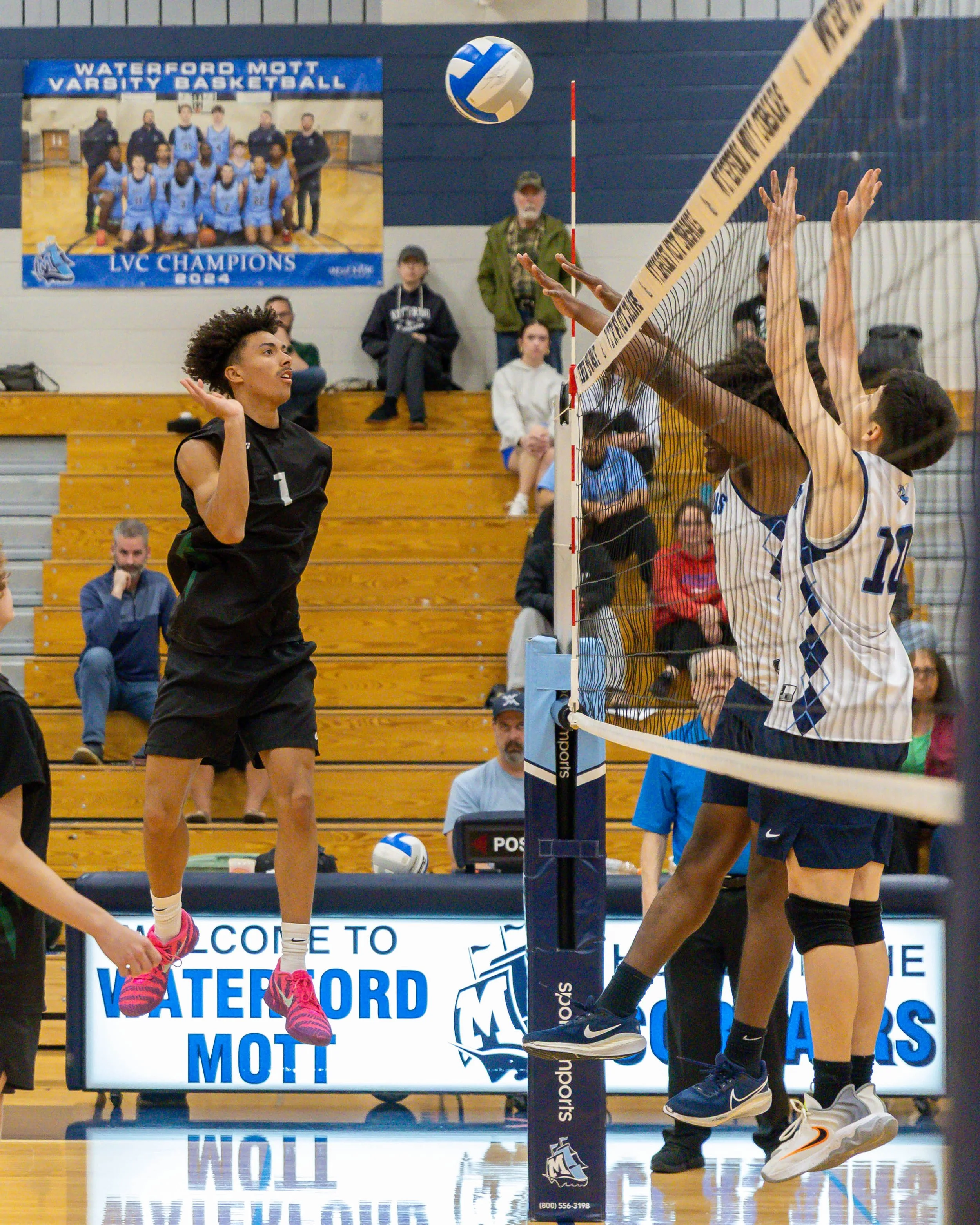 Kettering #1 spikes the ball and Mott #4 and #10 try to block it