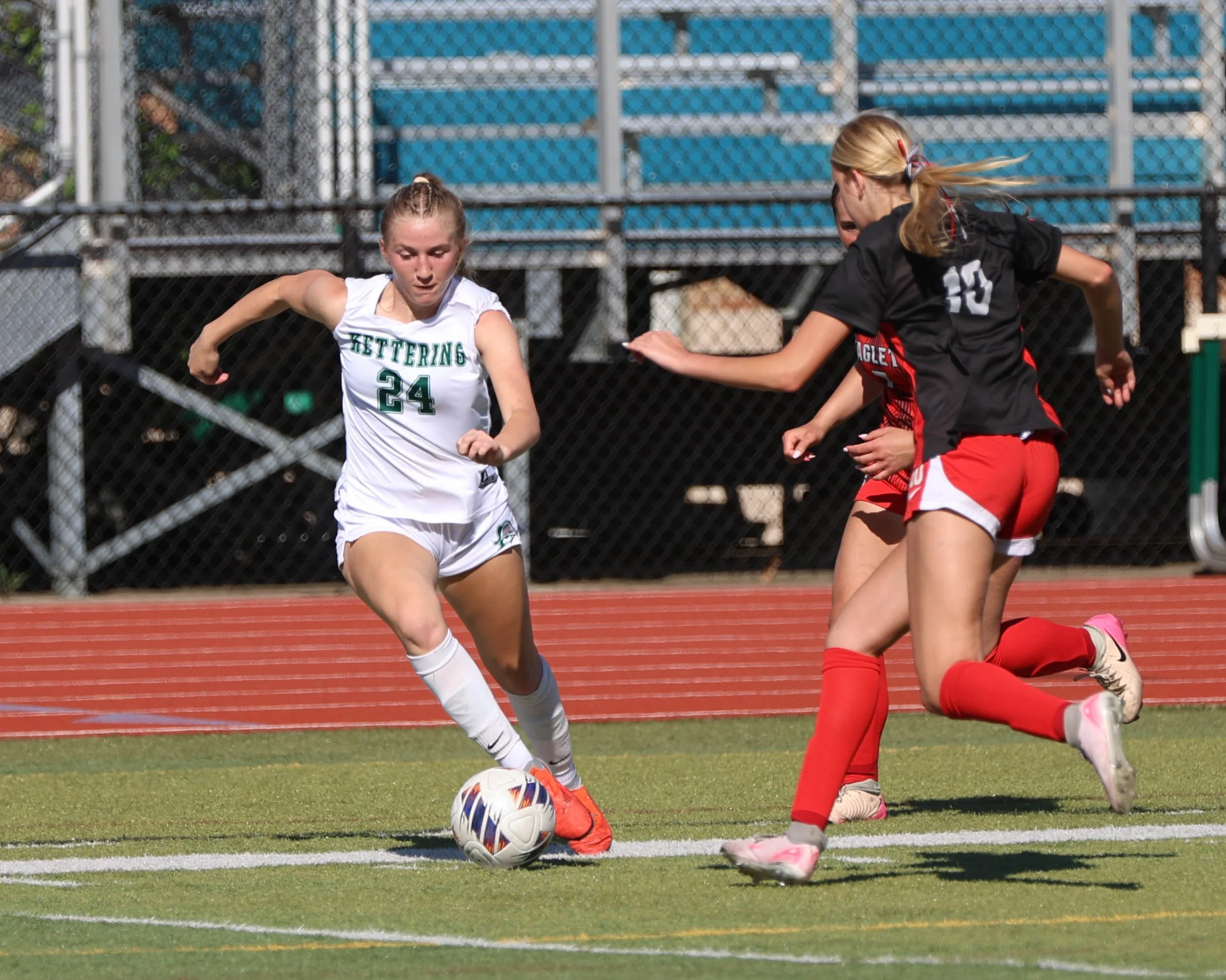 #24 kicks the ball past two defenders