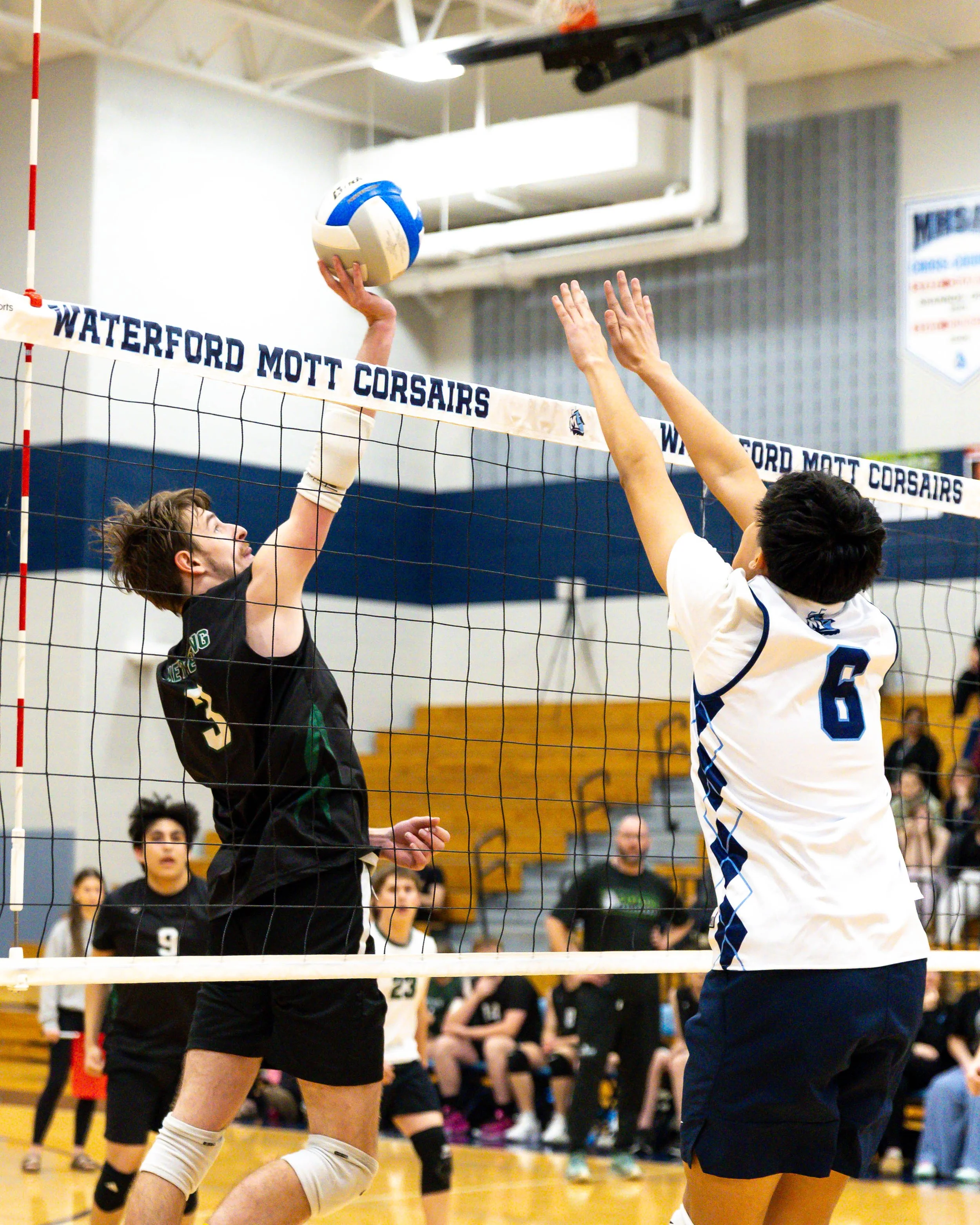 Kettering #3 hits the ball with Mott. #6 trying to block it