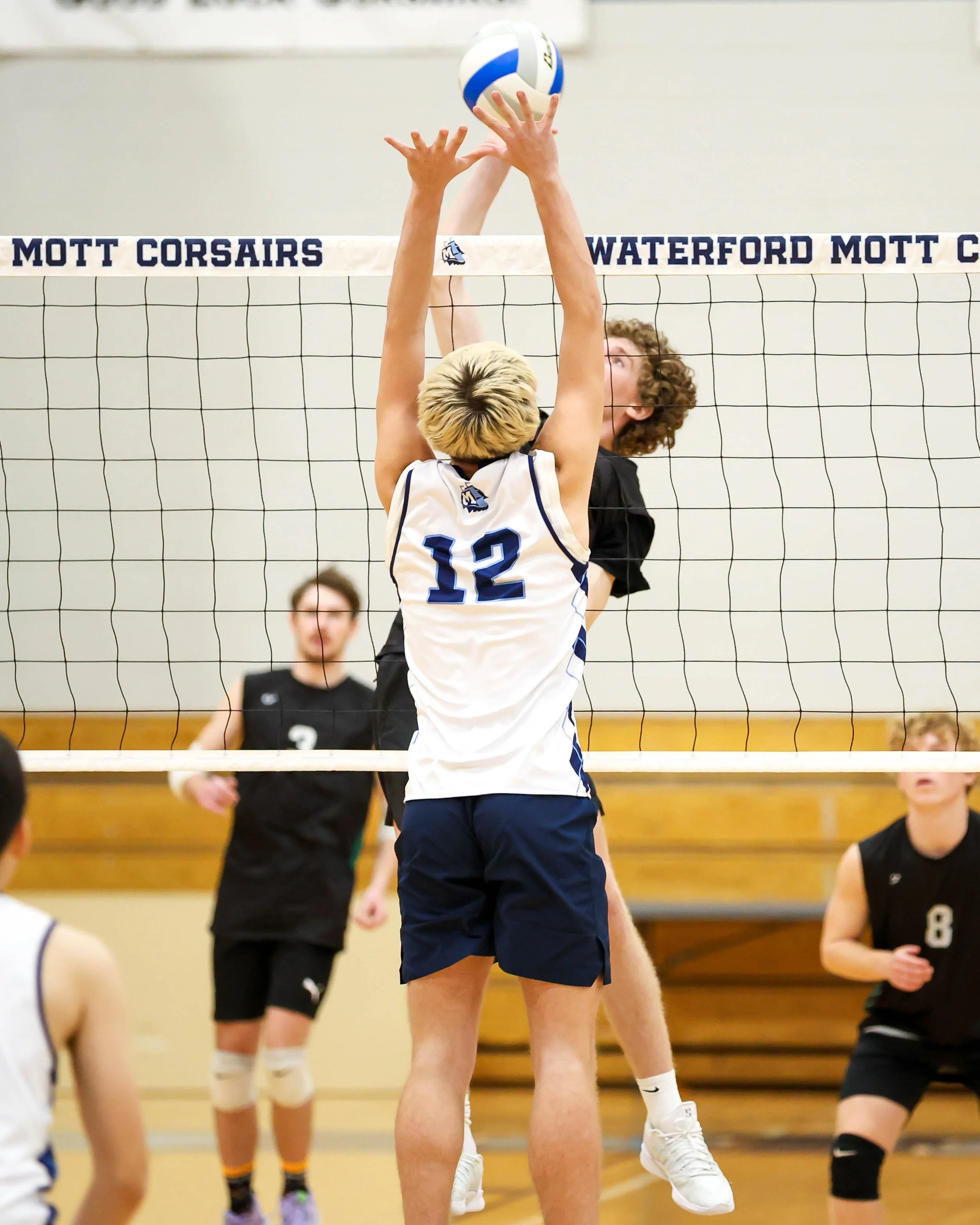 Kettering #12 spikes the ball with Mott #12 tries to block it