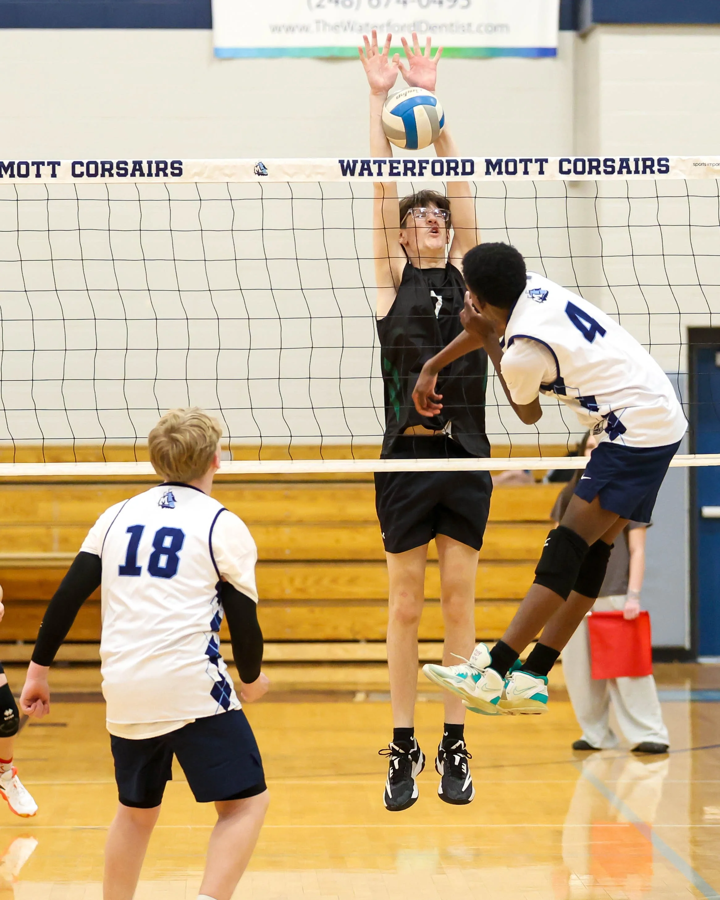 Mott #4 spikes the ball with Kettering #7 trying to block it