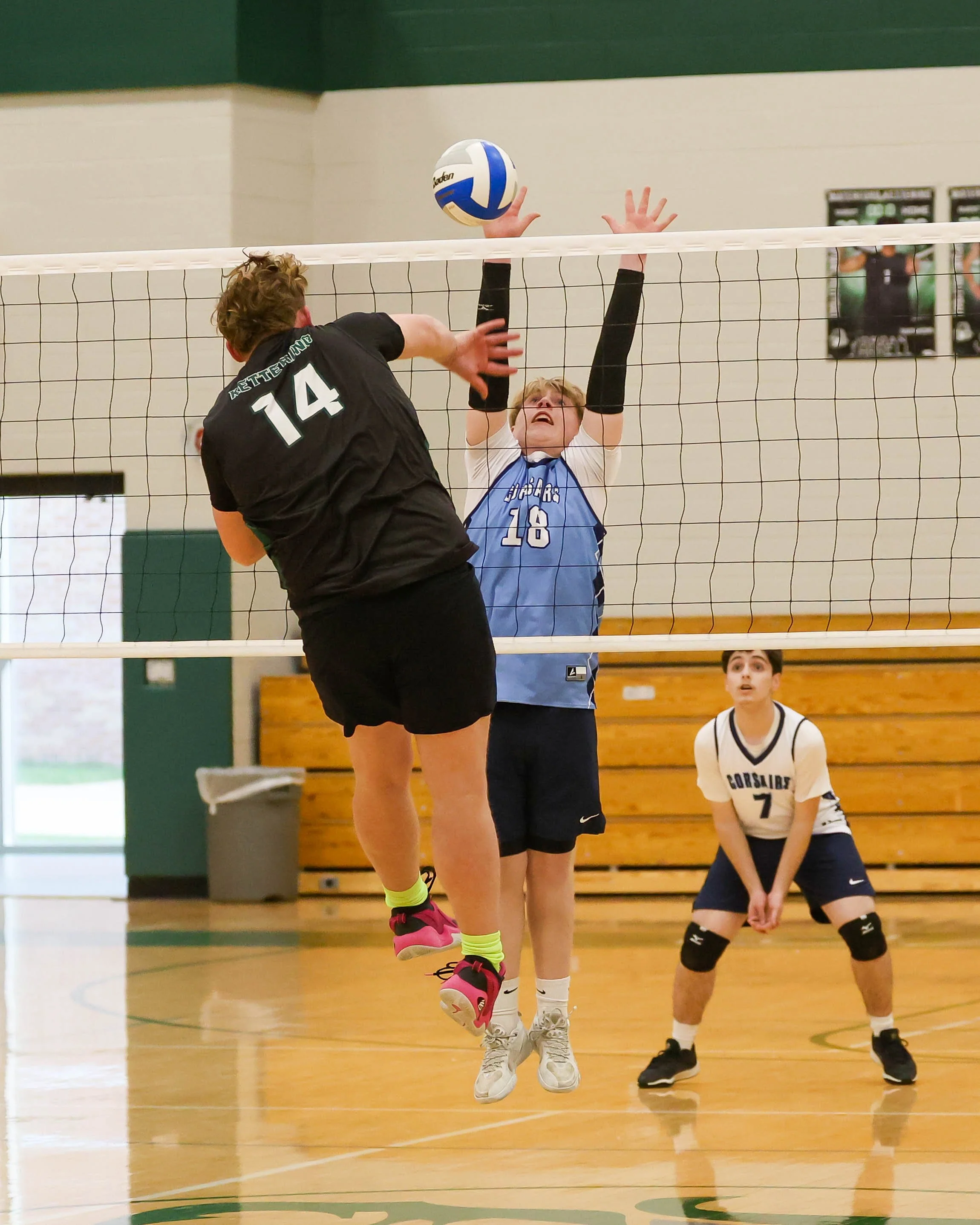 Kettering #14 spikes the ball with Mott #18 trying to block it