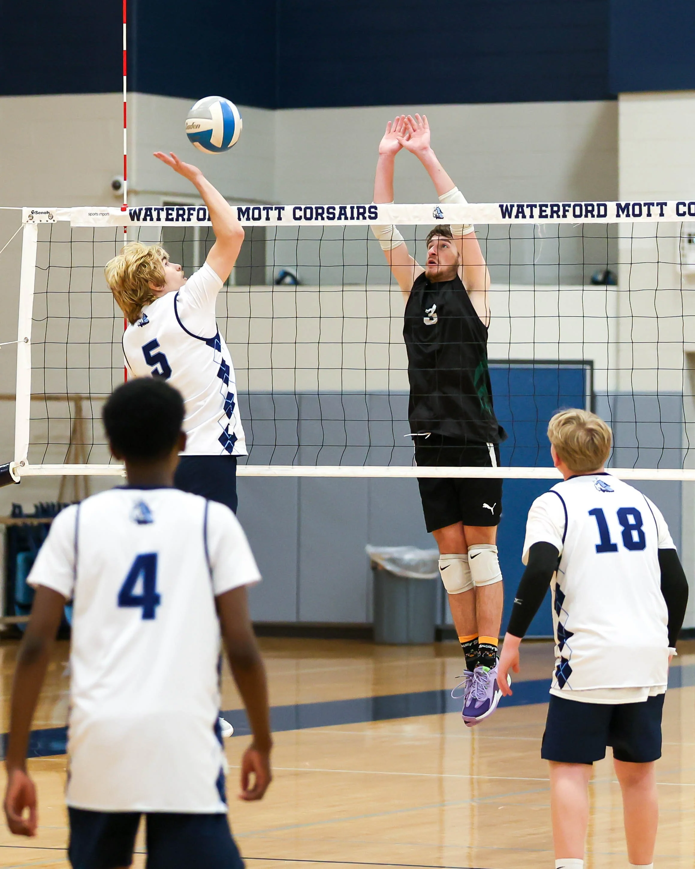 Mott #5 hits the ball and Kettering #3 tries to block it