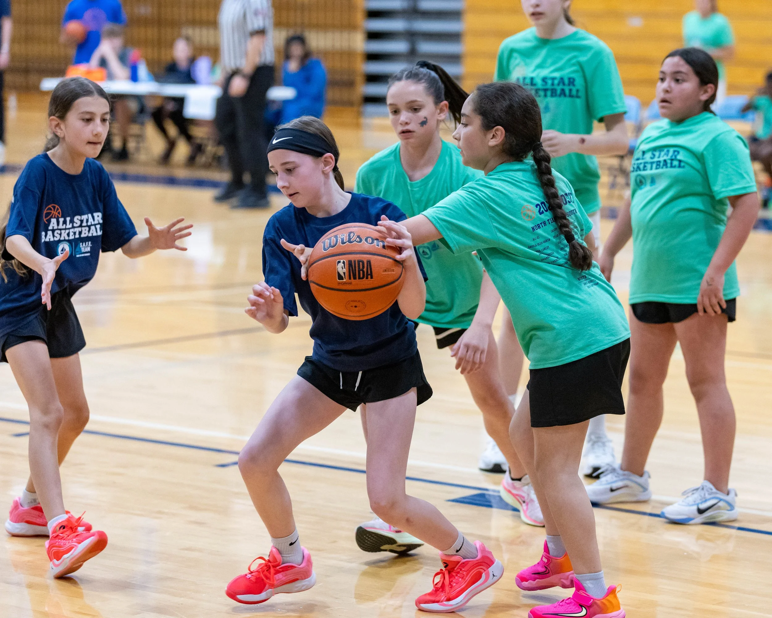 North girl dribbles the ball with South girl guarding her