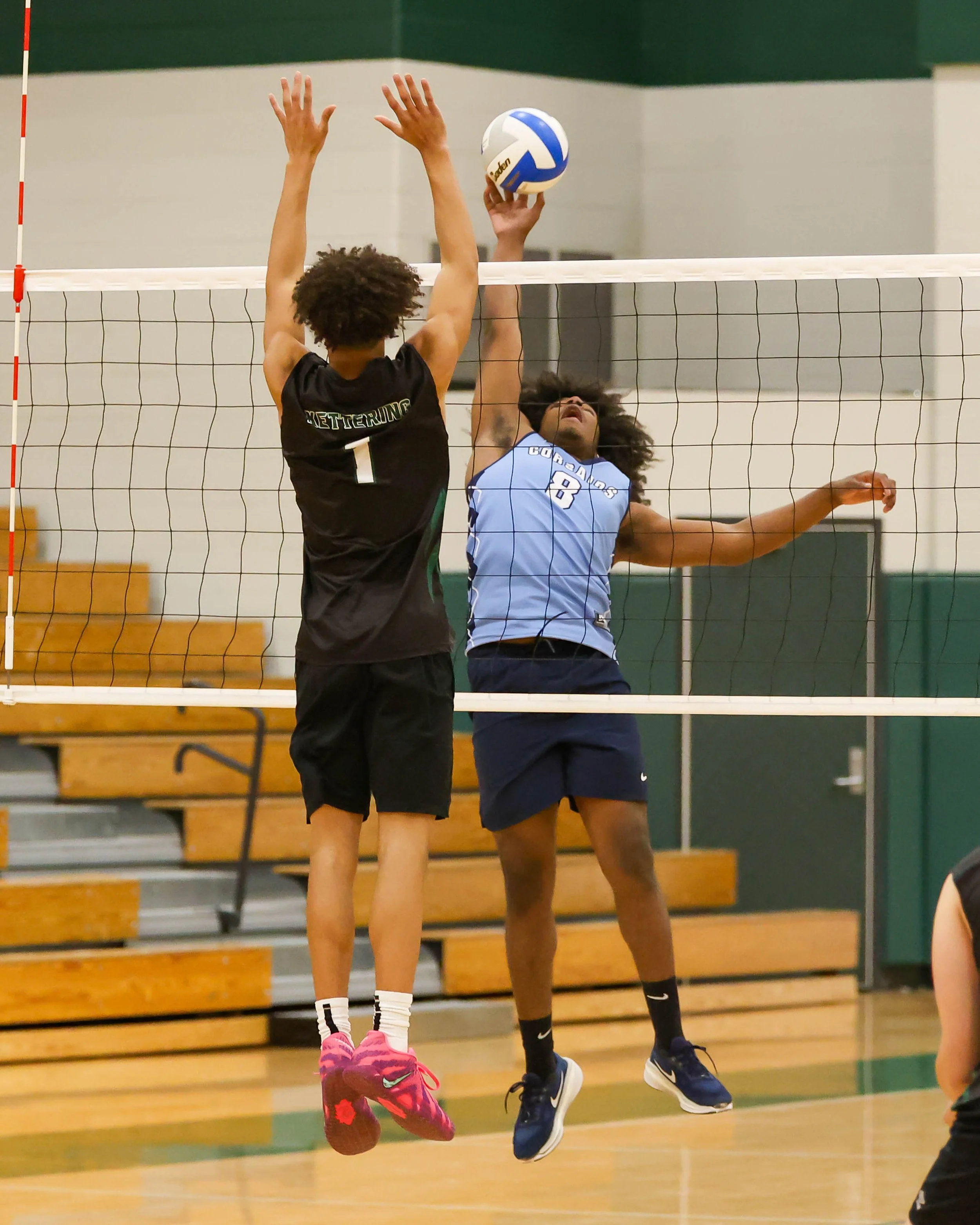 Mott #8hits the ball with Kettering #1 trying to block it