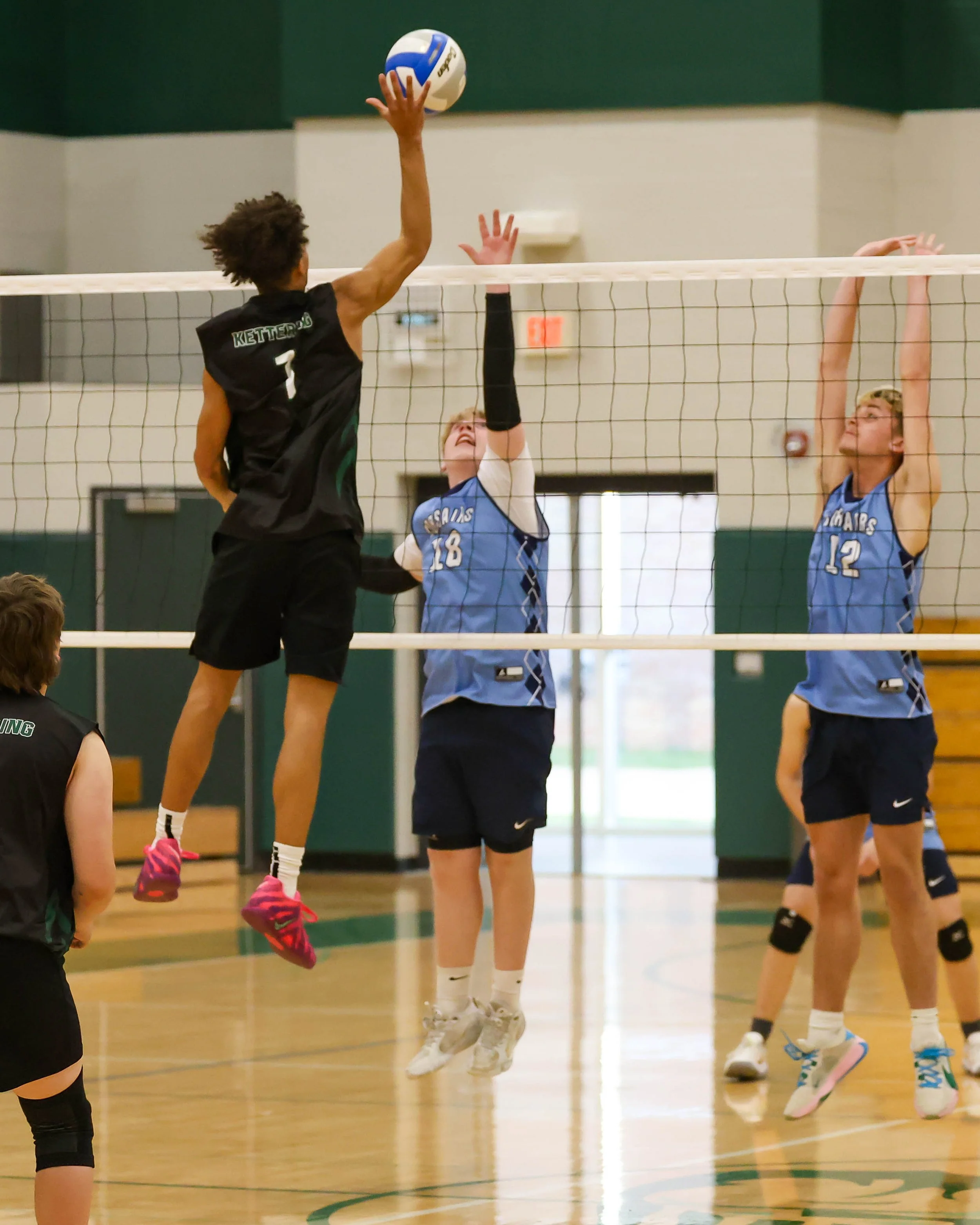 Kettering #1 hits the ball with Mott #18 and #12 trying to block it