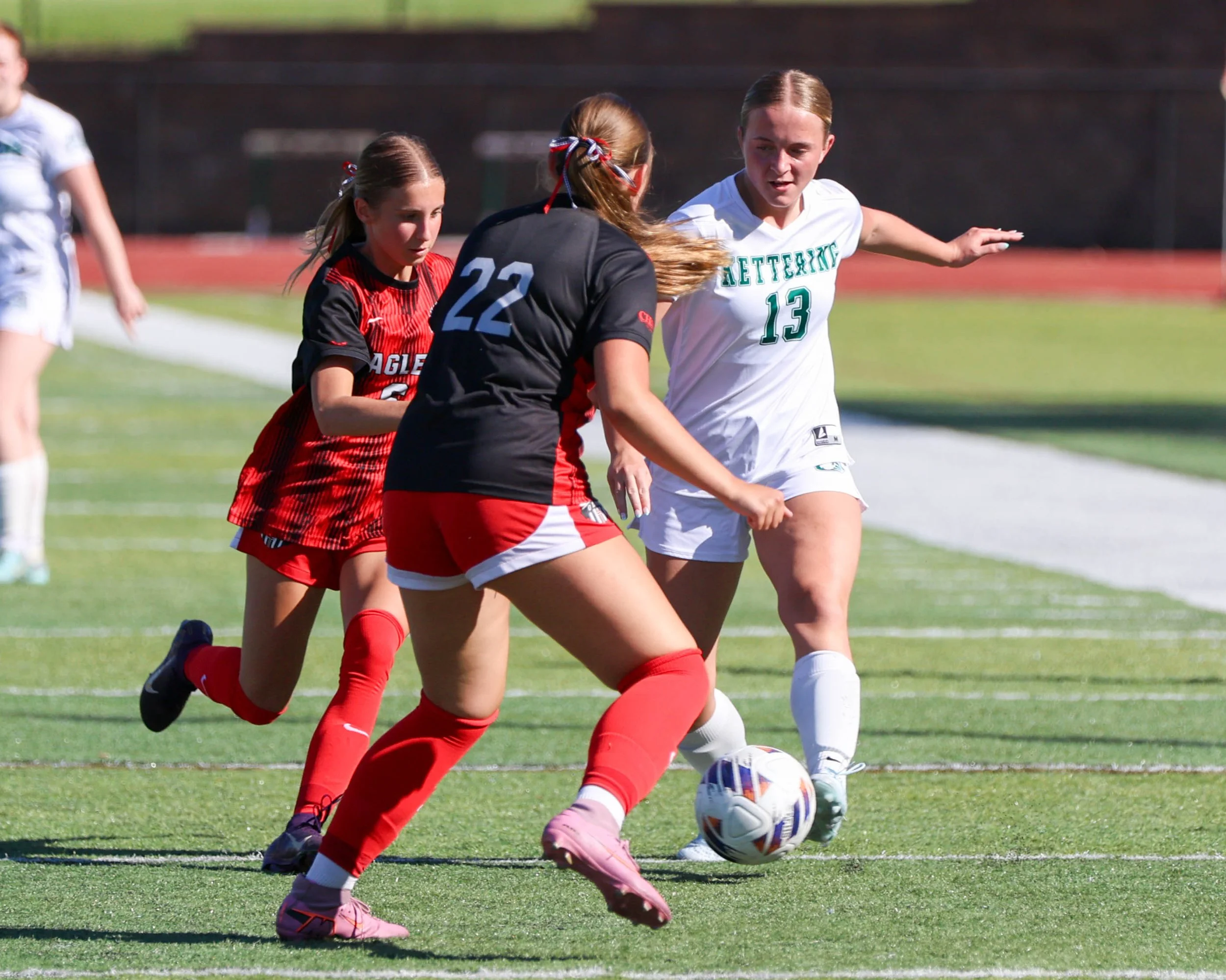 #13 with the ball against two defenders
