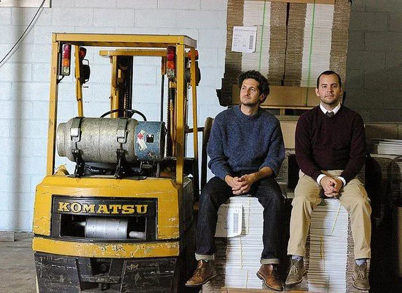 Dave Roma (left) and Paul Hanan (right) hang out at the whip cream factory by the forklift, which they may or may not use in the tie making process. Their bond of friendship made certain by their matching Clarks desert boots, passion for skateboardi…