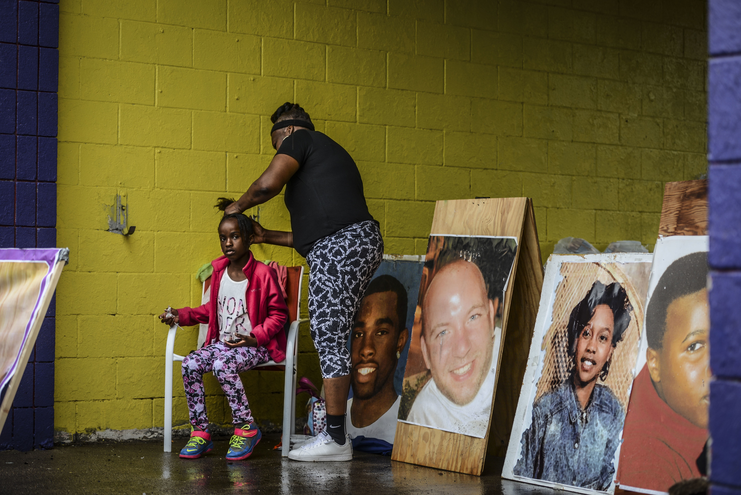  Jacqueline Thompkins does her granddaughter's hair, Dakari Thomkins, &nbsp;8-years-old, during a gathering after an organized march in response to the spike in violence on the city's southeast side, Saturday, Aug. 29, 2015, at Franklin Street and Ea
