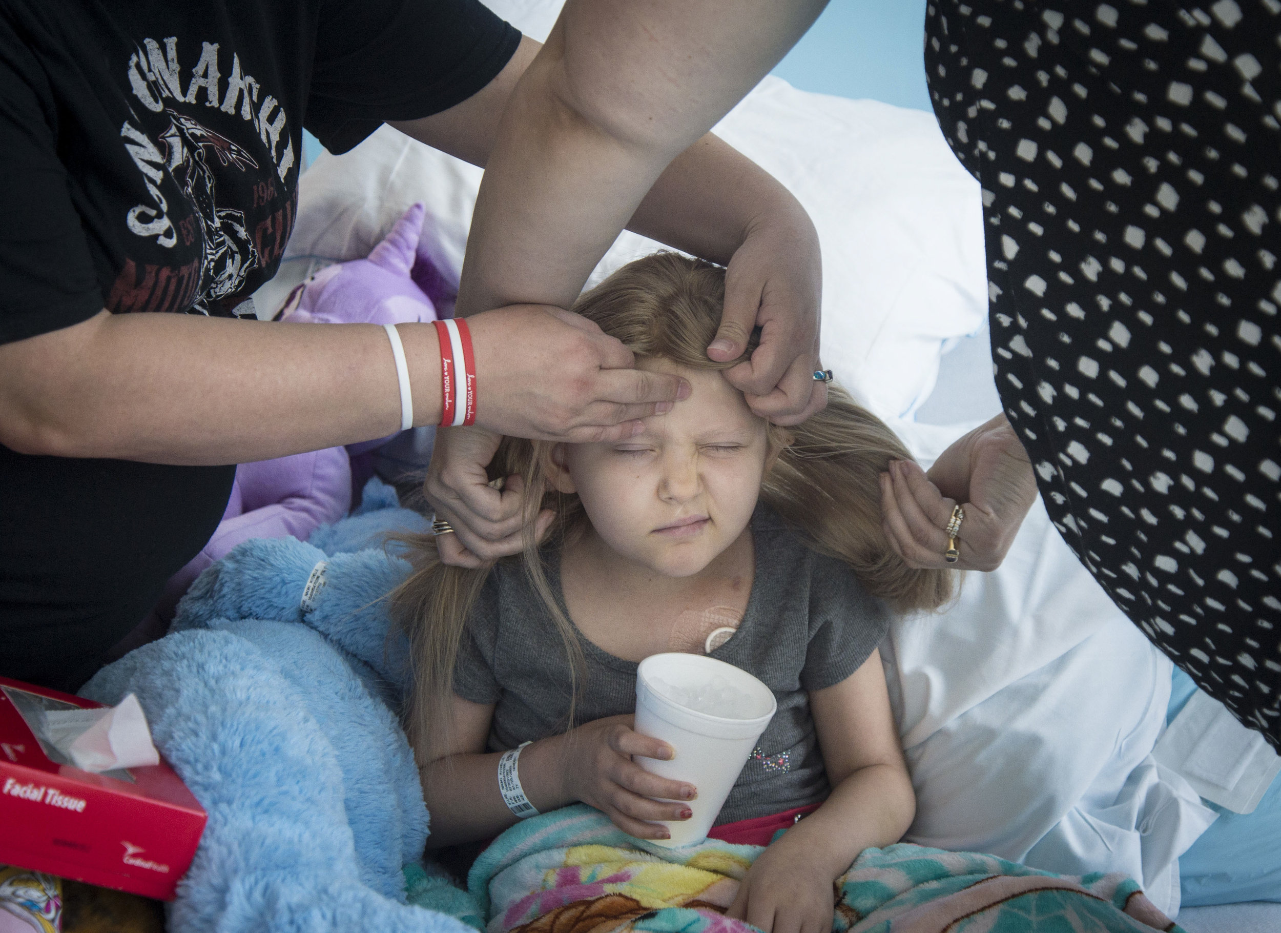  Naomi scrunches her face as her mother Donna and Sharon Potter, the owner of Salon Nouveau, whom delivered her wig made of donated human hair from the charity Children with Hair Loss, fit it on her head. After a long day of chemo and pain from a rec