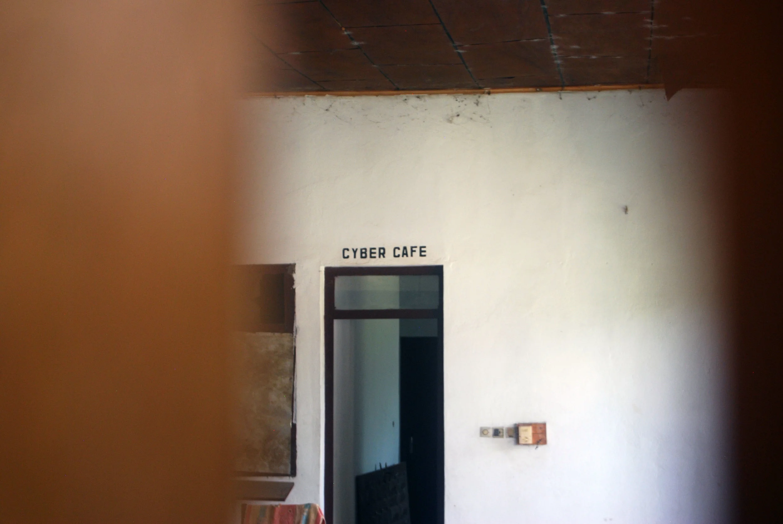 A picture of the Cyber Café entrance, taken through the slats of a boarded up window in the abandoned luxury hotel at Boali Falls.
