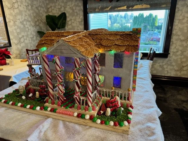 A gingerbread house decorated with candy canes, gumdrops, and colorful lights, placed on a table.