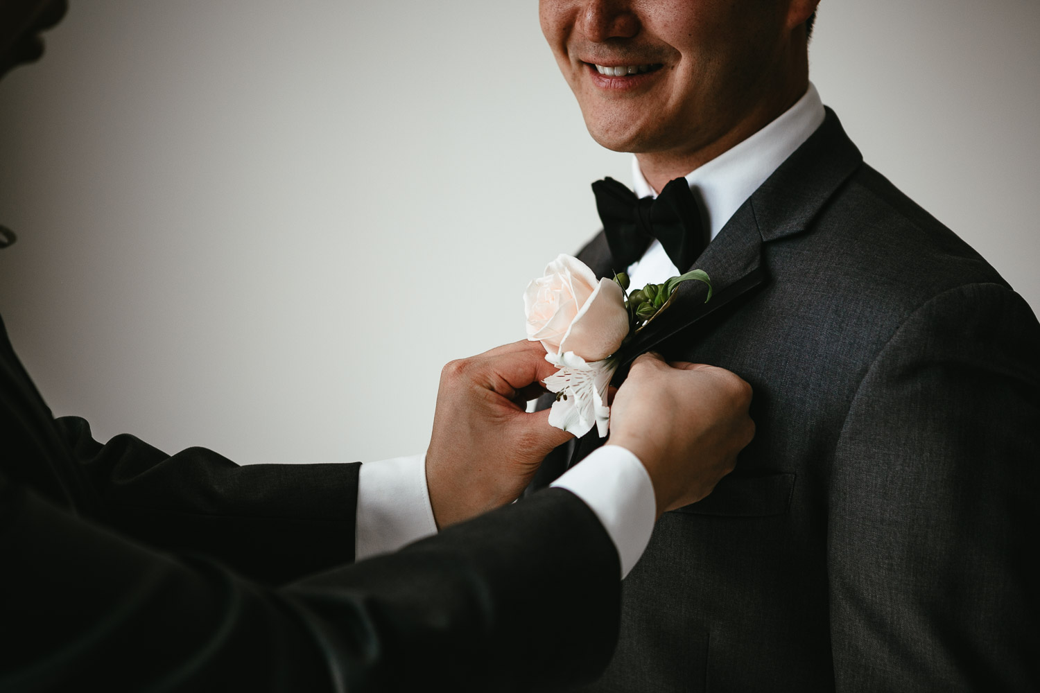 putting on boutonniere for groom in vancouver wedding photography