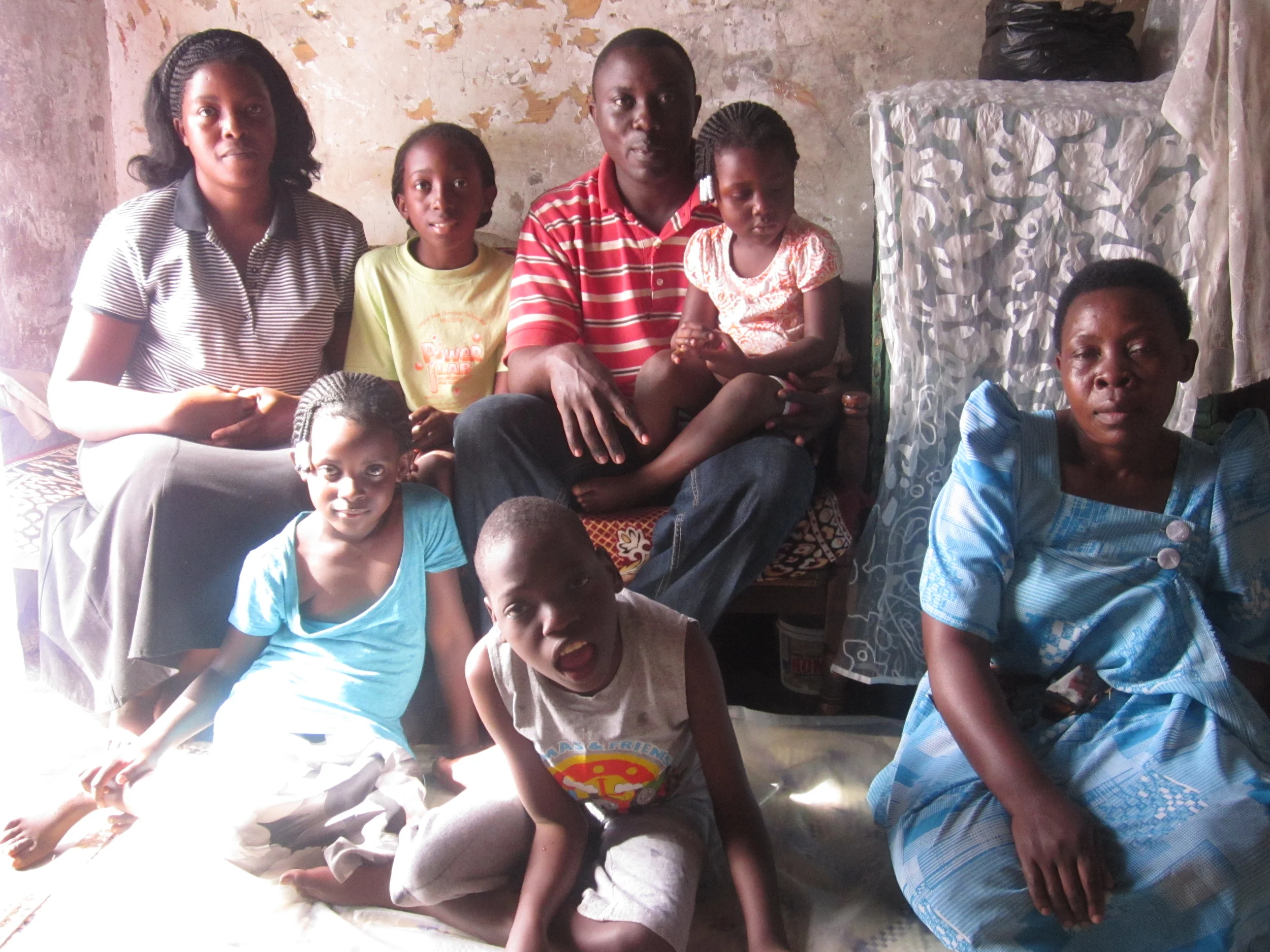 The Lawrence and Josephine Ssemakula family: sitting on bench: Josephine, Quinn, Lawrence and Genevieve, on floor: Genesis, Jeremiah, and Lawrence's mother.