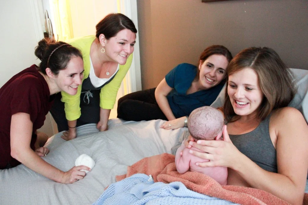 Surrounding Amanda to welcome baby Lenore is Tori Roufs (doula), Elise Buckner (apprenticing midwife), and Celesta Bargatze (newly certified midwife)—all of G.O.D. International—her primary midwife, a Licensed Certified Professional Midwife was also in attendance (not pictured). This picture speaks to the bond created and compassionate support a new mother can, and should, experience from her support team.