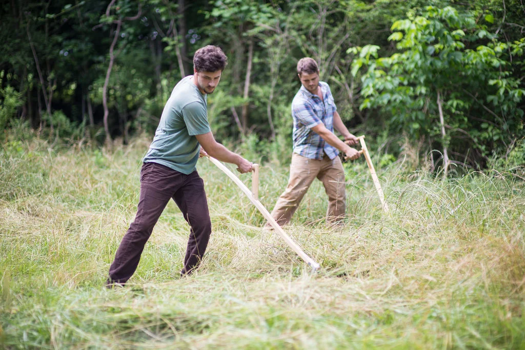 Cameron Kagay (back) began researching scythes and their benefits several years ago, while heavily involved with the agricultural efforts at the G.O.D. Int’l headquarters in Tennessee. Always eager to find ways to make the work of his African friends easier and safer, Kagay spearheaded the scythe project this summer. Kagay trained Gerard on the use, care, and effectiveness of the scythe in Tennessee before Gerard transferred them to Uganda.