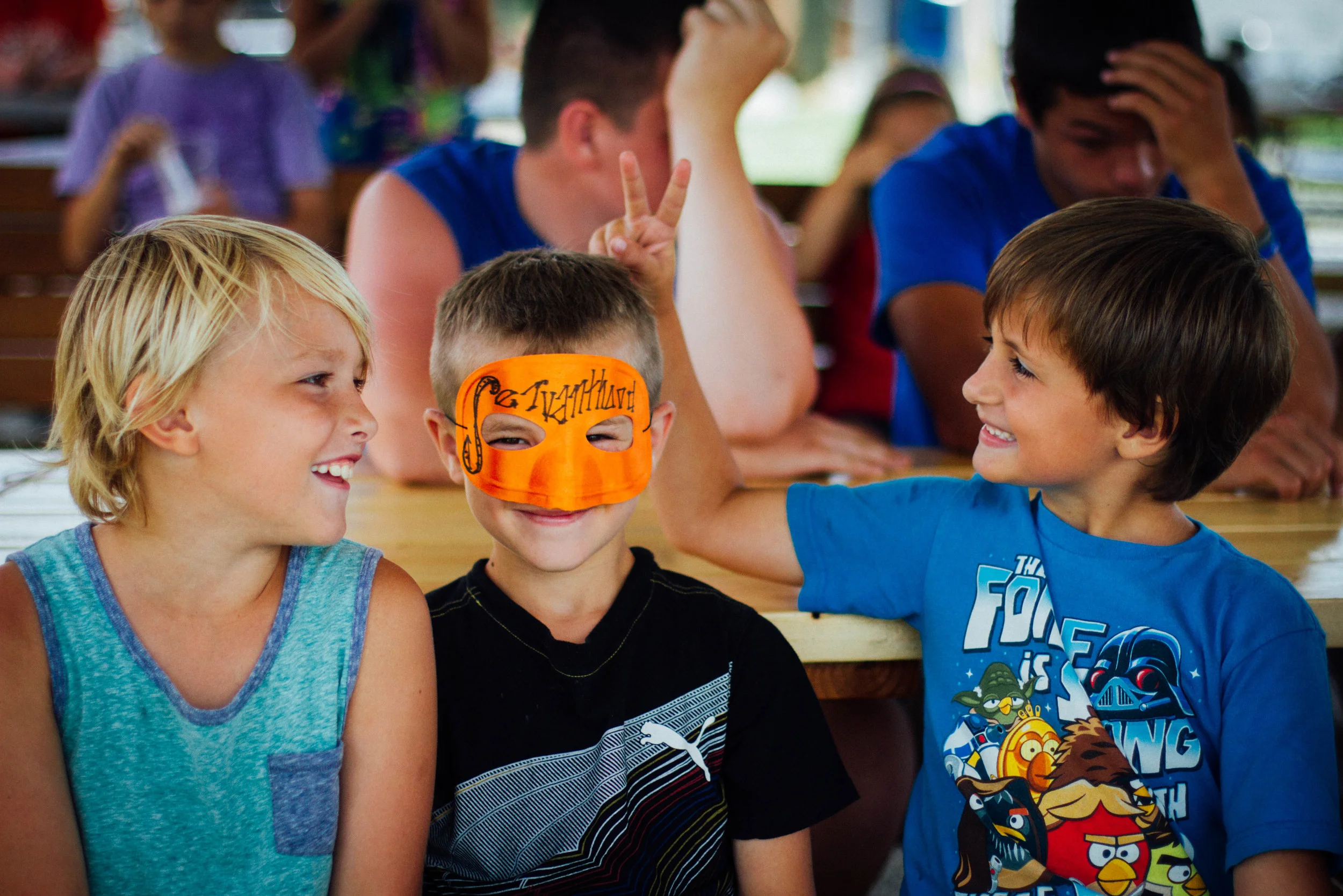 Elijah Galford, Eved Roufs, and Elijah Smith enjoy lunch at the picnic tables that the boys helped build. Eved dons a “superhero” mask that reads “servanthood”–the most heroic of all traits, and also, the meaning of his name (Eved means “servant” in Hebrew). Eved received the mask after displaying servanthood to other campers and counselors throughout the week.