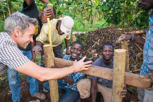 Davis works with local farmers to level a stand to hold the water bucket for the irrigation system.